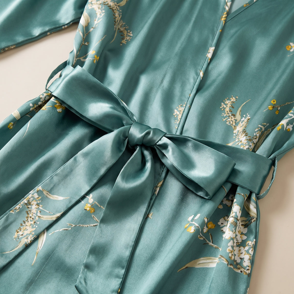 Détail du semis floral crème et du noeud de ceinture en satin vert céladon