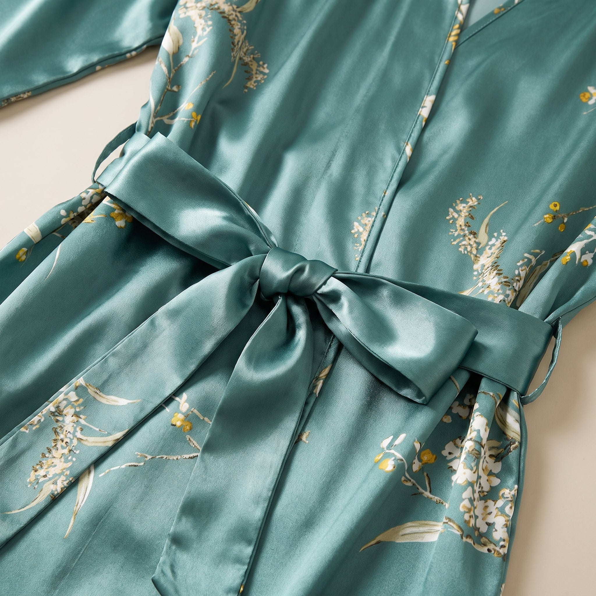 Détail du semis floral crème et du noeud de ceinture en satin vert céladon Image