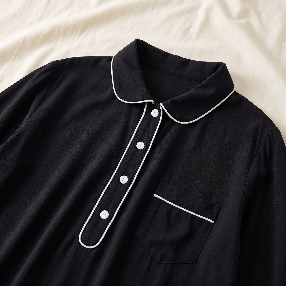 Col arrondi, quatre boutons blancs et passepoil de la chemise de nuit noire
