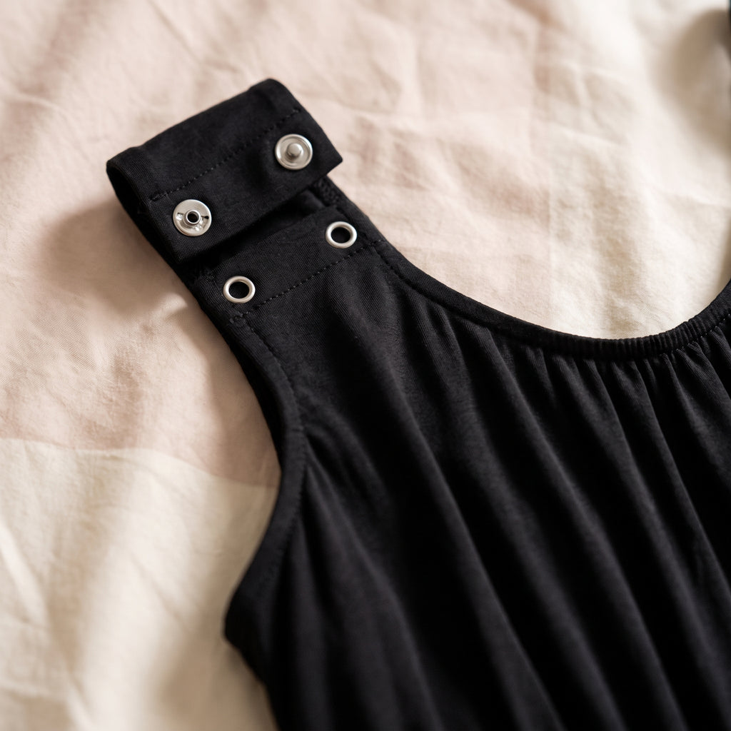 Gros plan sur une bretelle de la nuisette noire et ses deux boutons-pression d'allaitement, ouverts sur l'épaule