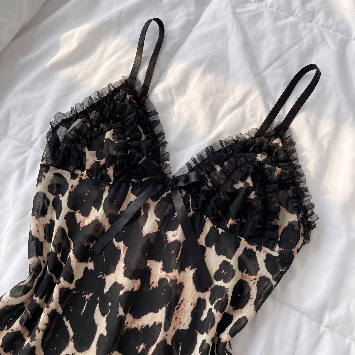 Détail du décolleté en V à volant de tulle noir et noeud de satin de la nuisette
