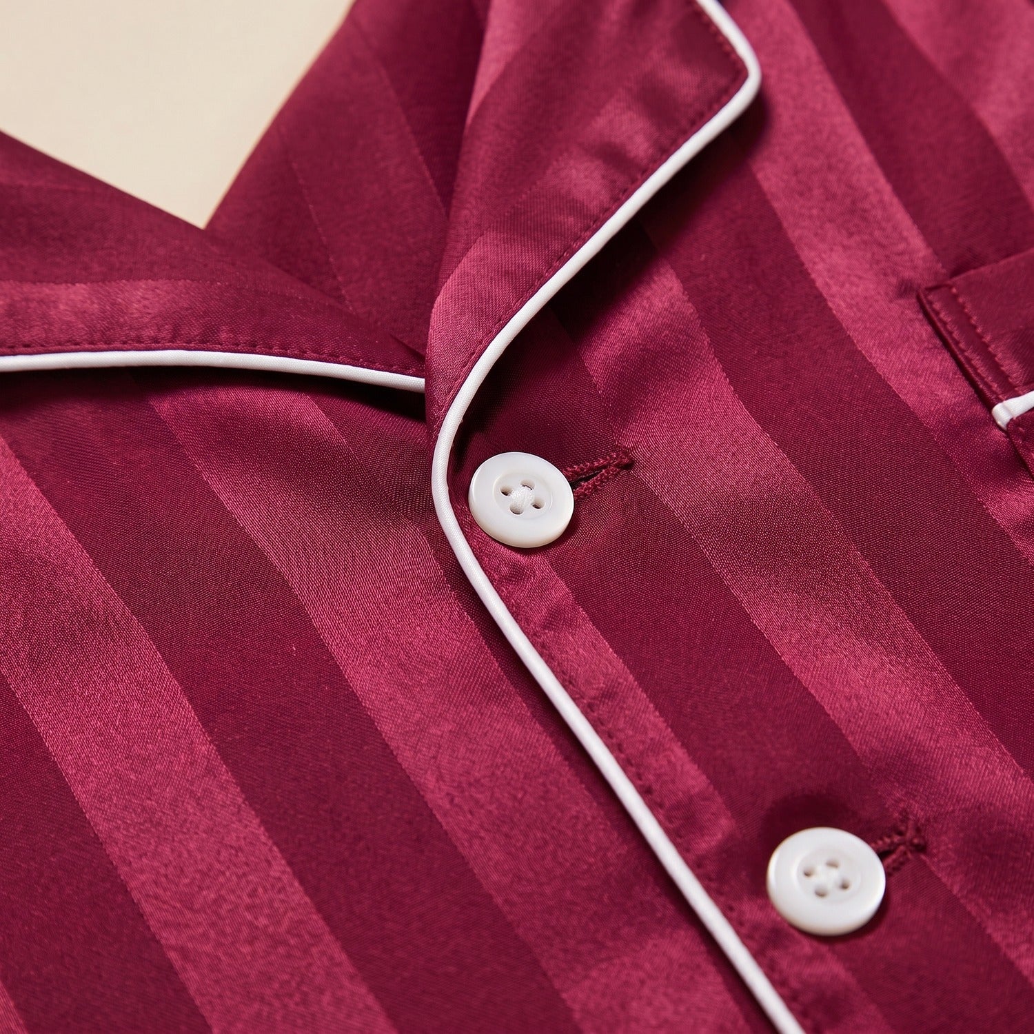 Gros plan détail du passepoil blanc et des boutons du pyjama homme satin bordeaux Image