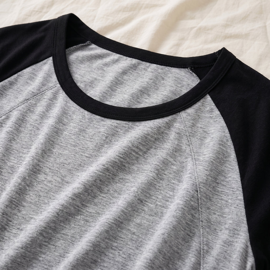 Galon noir de l’encolure et départ d’une couture raglan, vus de près sur le jersey chiné