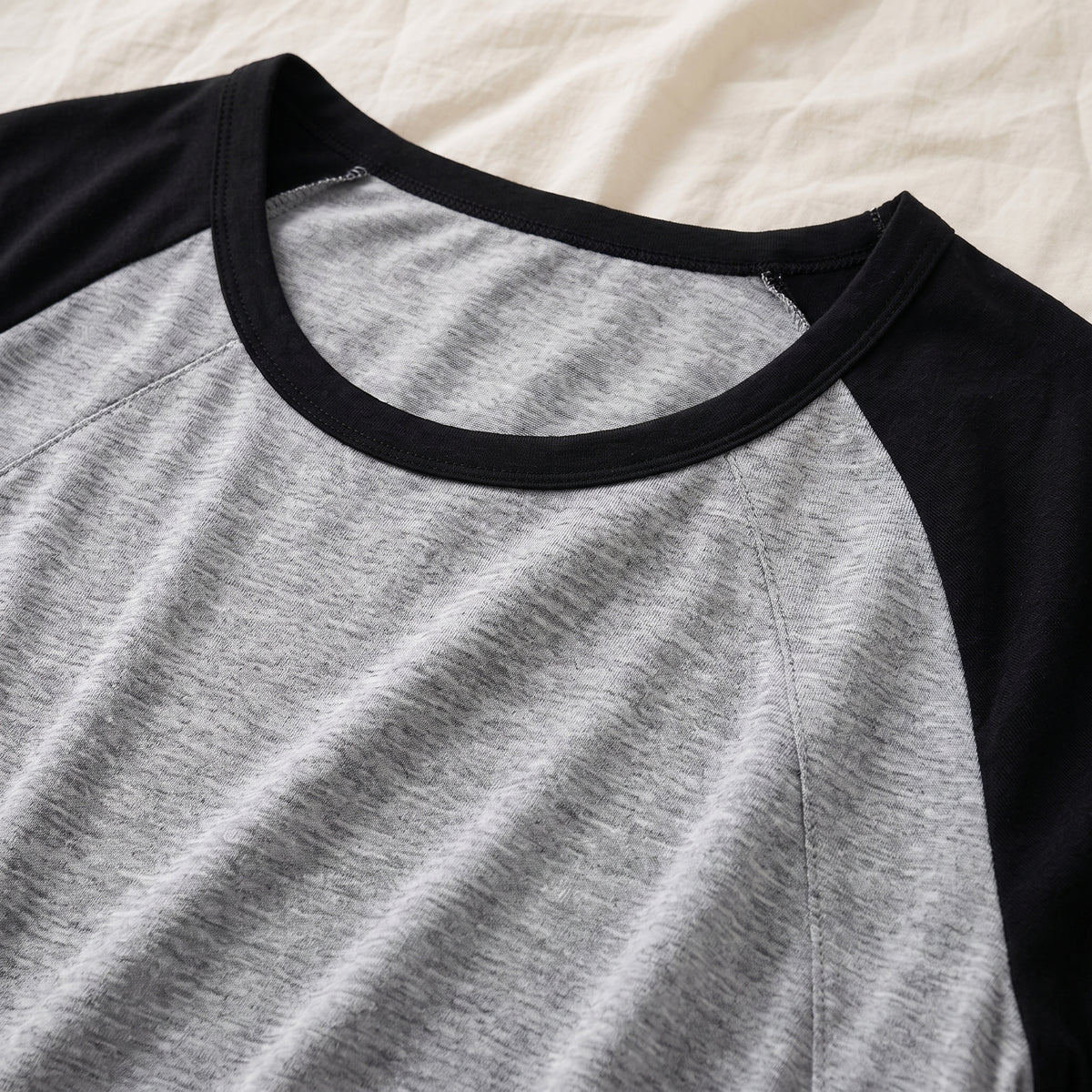 Galon noir de l’encolure et départ d’une couture raglan, vus de près sur le jersey chiné
