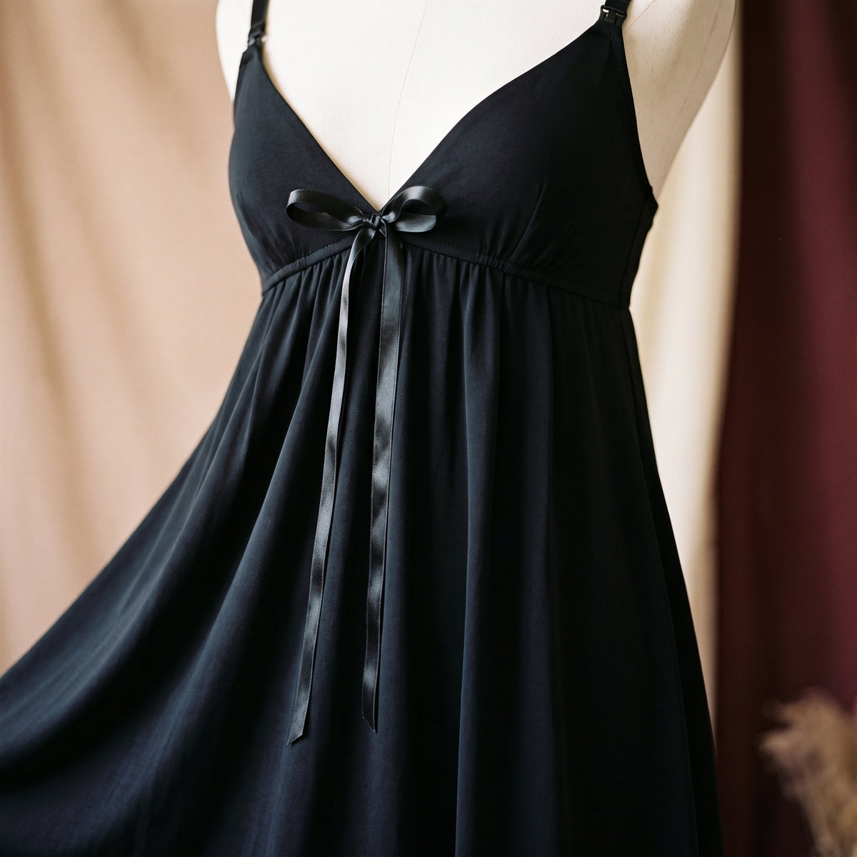 Nœud de satin noué sous la poitrine de la nuisette noire, la jupe s’évase en dessous