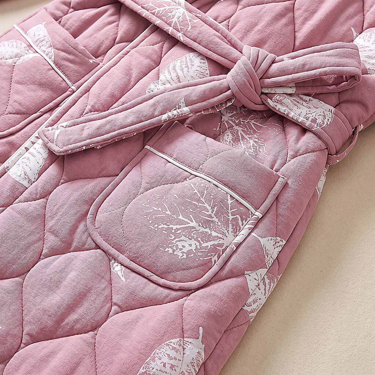 Détail du matelassage ouaté rose à surpiqûres, d'une poche et de la ceinture