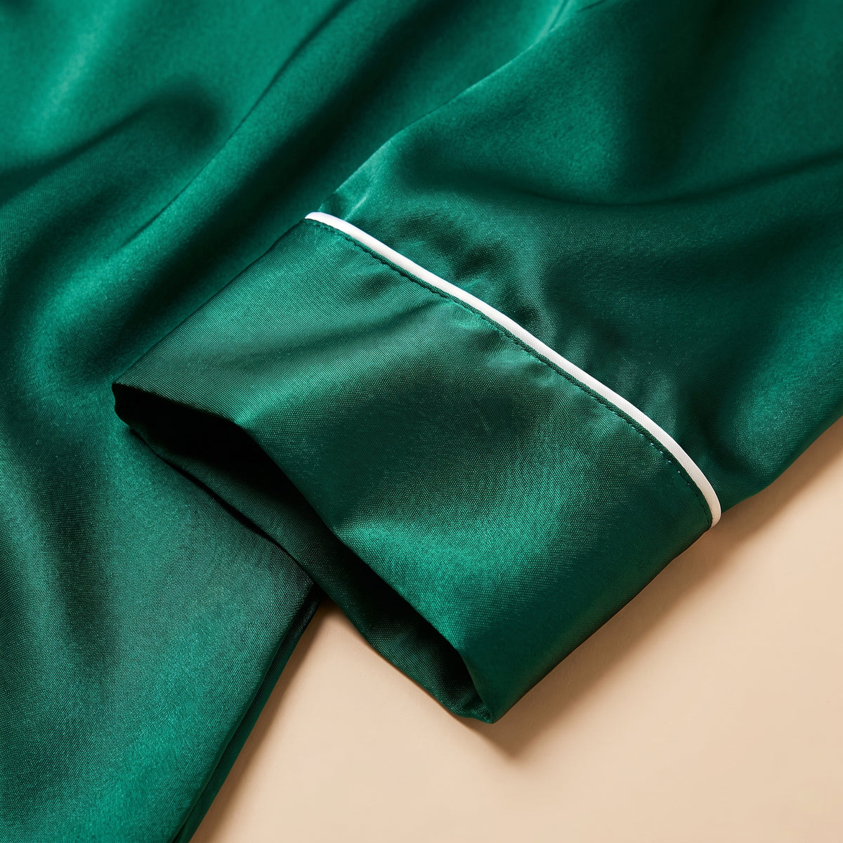 Détail du satin vert lumineux et du poignet à passepoil blanc