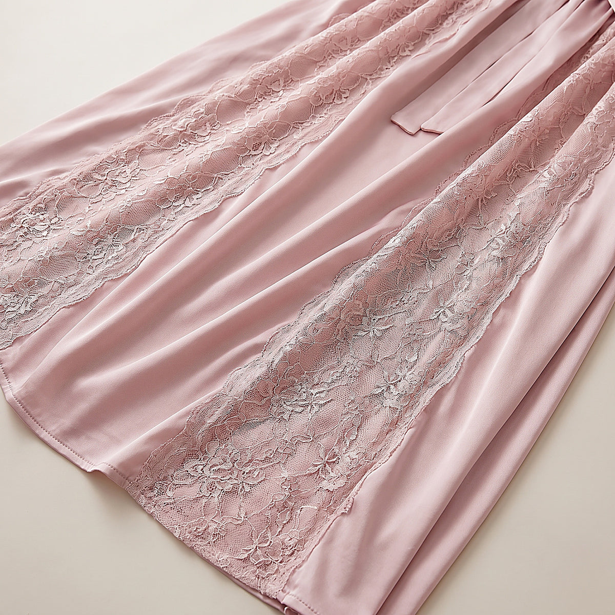 Détail des panneaux de dentelle florale et du satin rose poudré