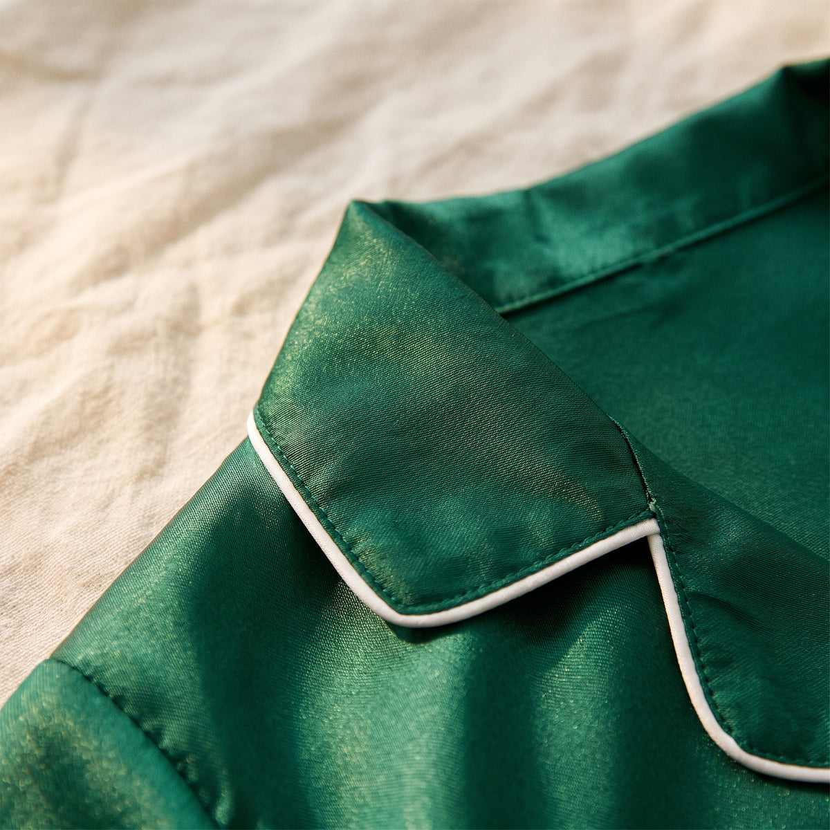 Gros plan sur la pointe du col à revers d'un pyjama fille vert et sur le liseré blanc qui en borde le bord