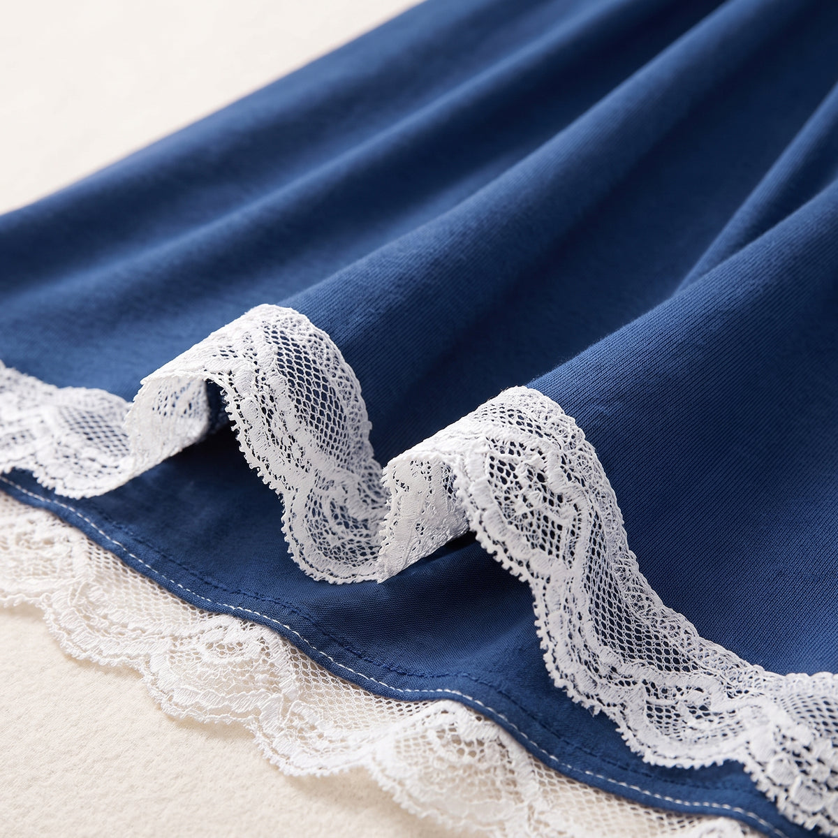 Détail de l'ourlet en dentelle blanche et du jersey bleu nuit