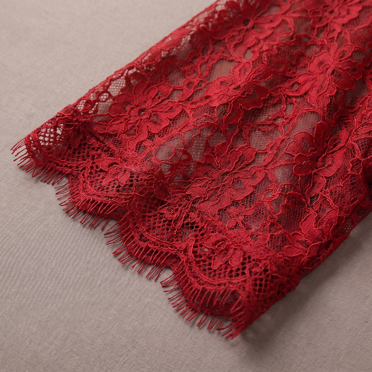 Détail de la dentelle rouge transparente et du volant de la manche