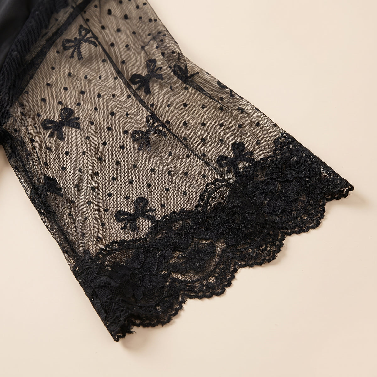 Détail de la manche du kimono en voile noir à pois bordée de dentelle