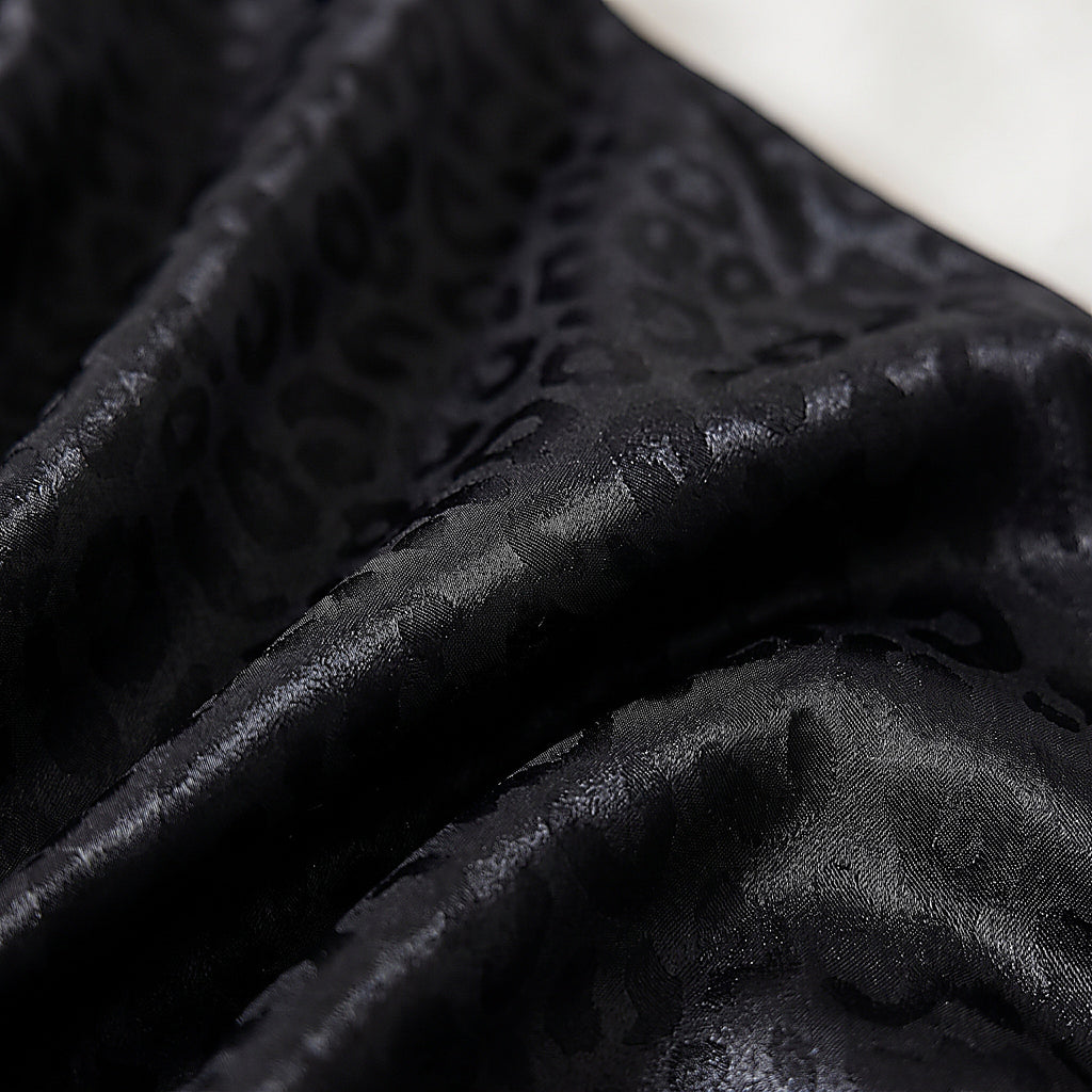 Détail du motif léopard ton sur ton du satin noir du pyjama