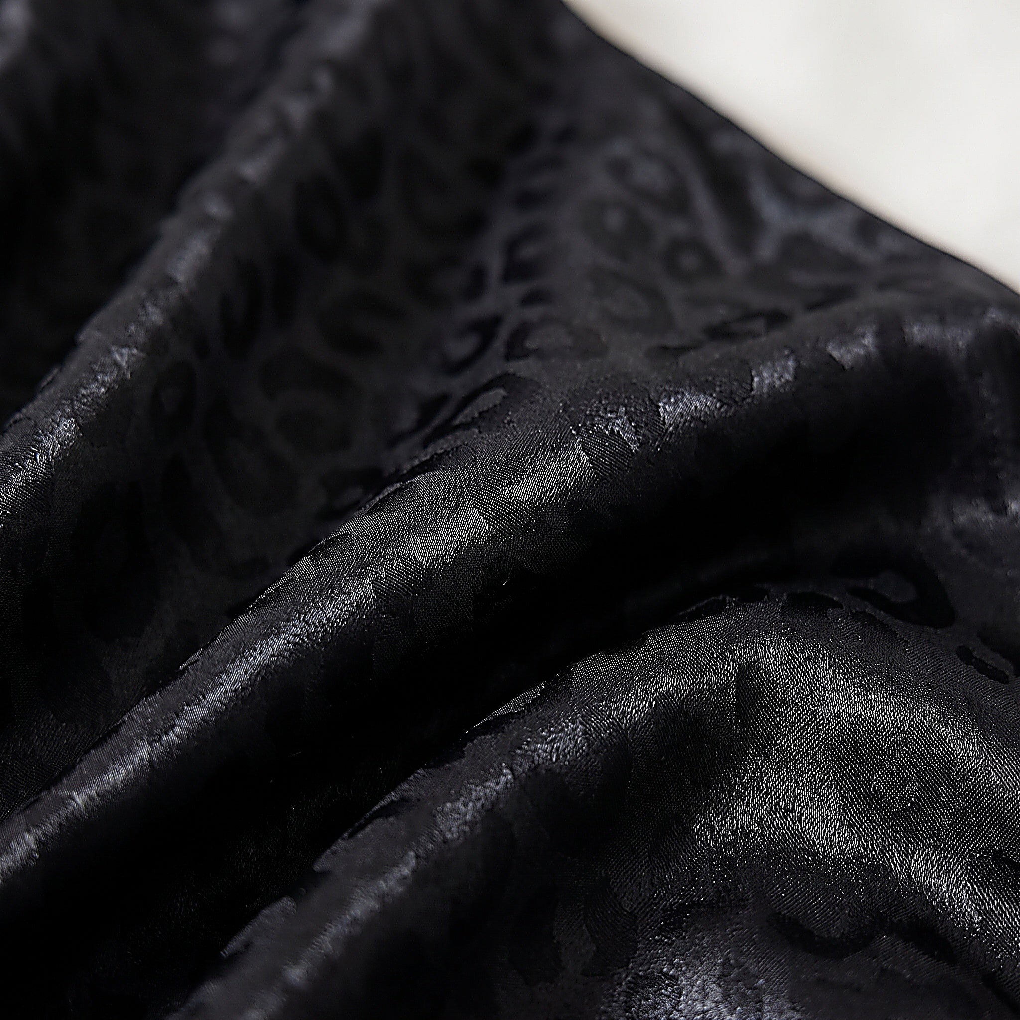 Détail du motif léopard ton sur ton du satin noir du pyjama Image