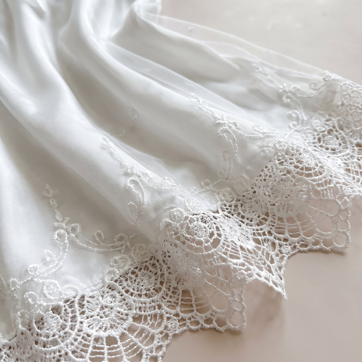 Détail de l'ourlet en dentelle ornée et du satin blanc