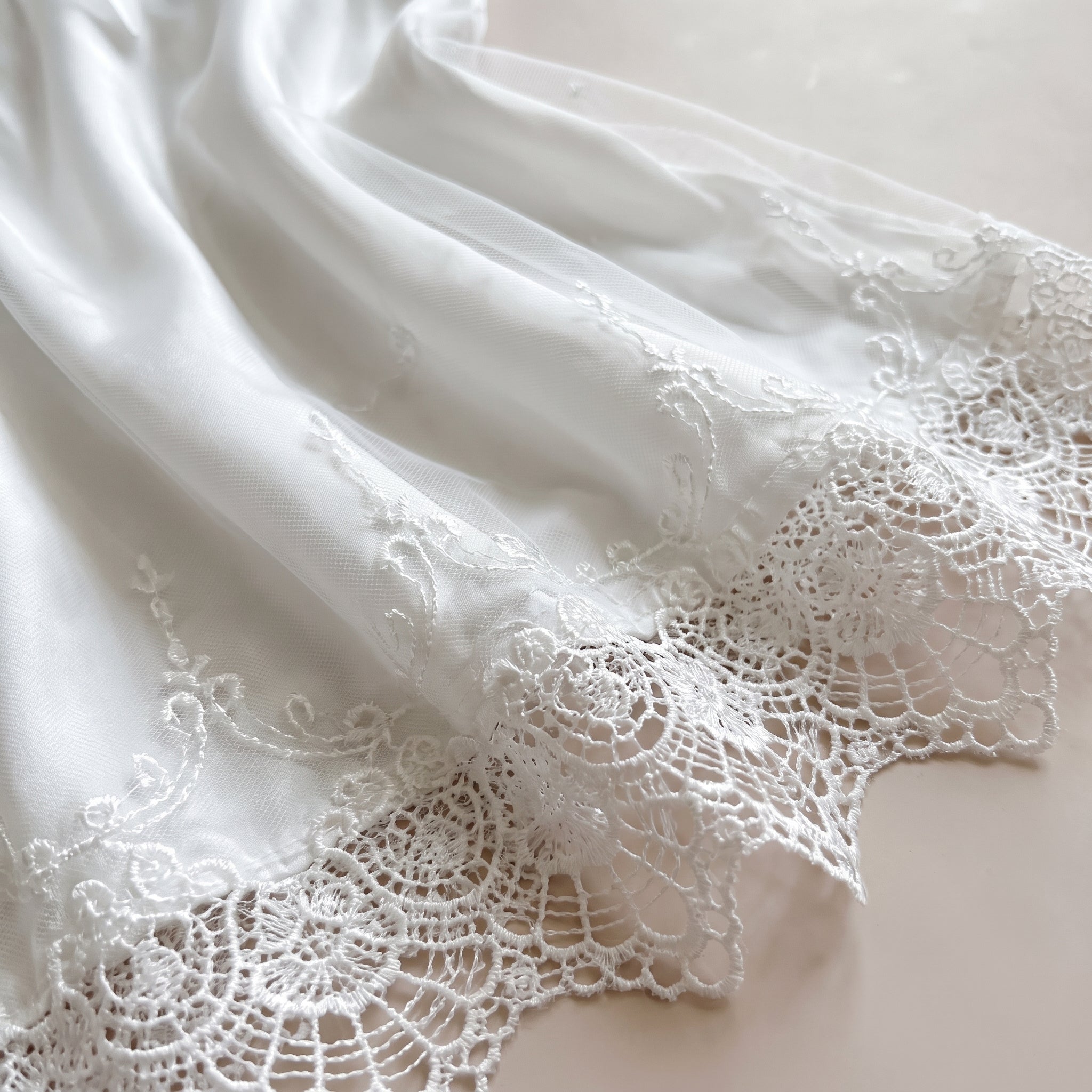Détail de l'ourlet en dentelle ornée et du satin blanc Image