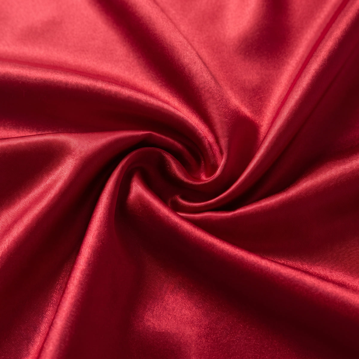 Détail du satin rouge lumineux et fluide de la longue jupe