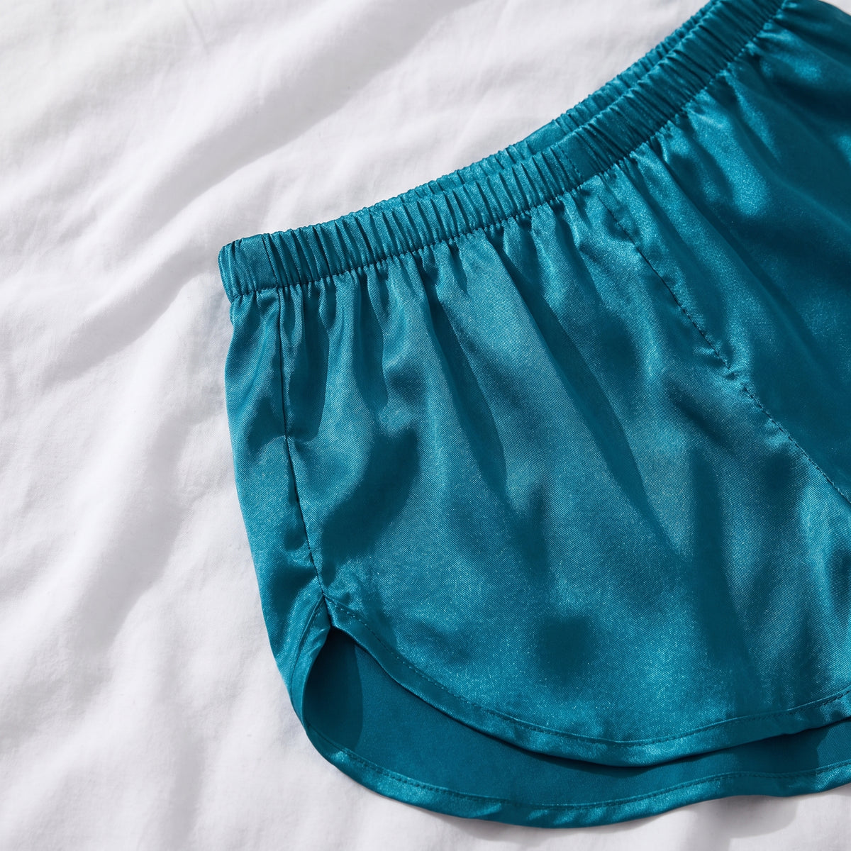 Détail de la taille élastique froncée et du côté arrondi du short en satin bleu canard