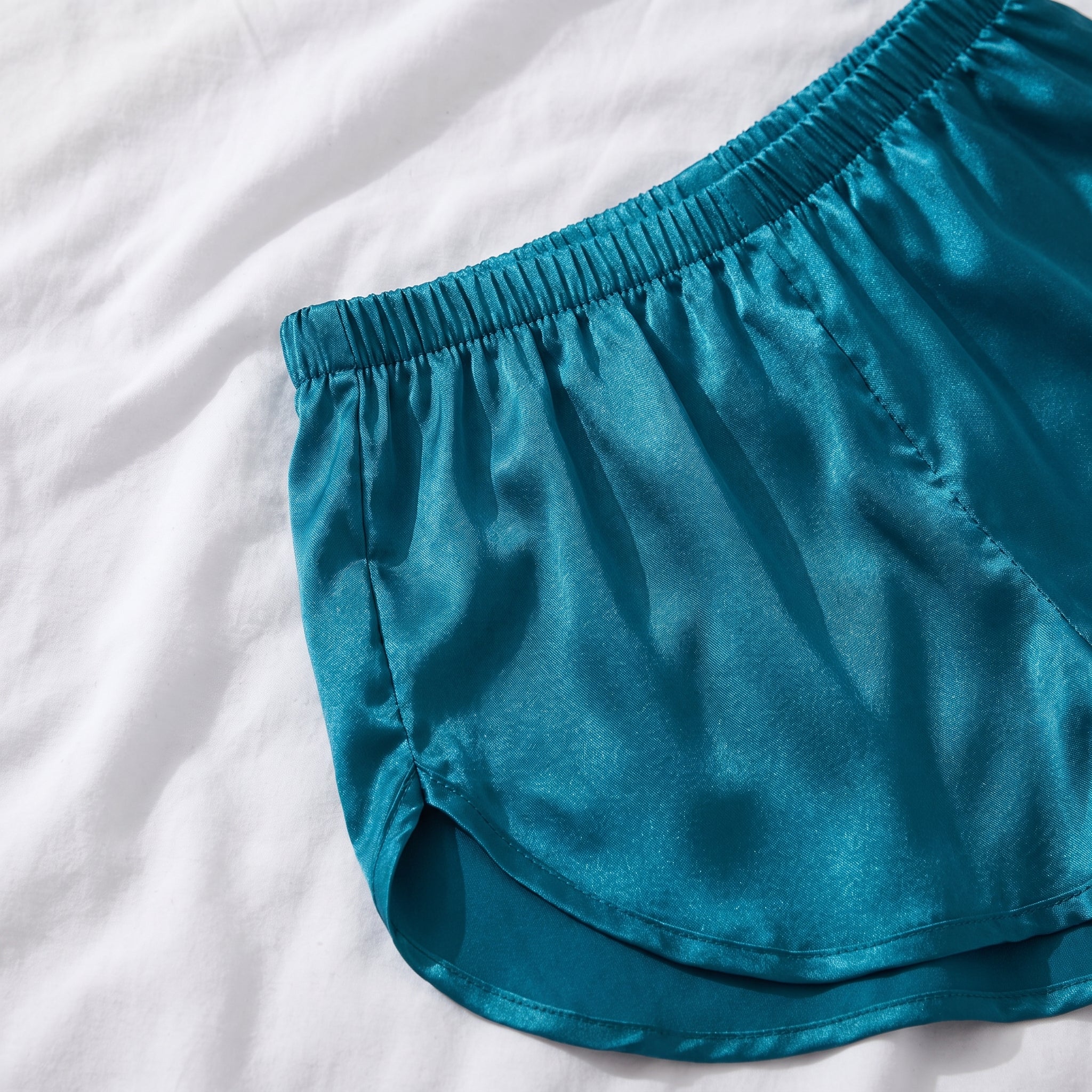 Détail de la taille élastique froncée et du côté arrondi du short en satin bleu canard Image