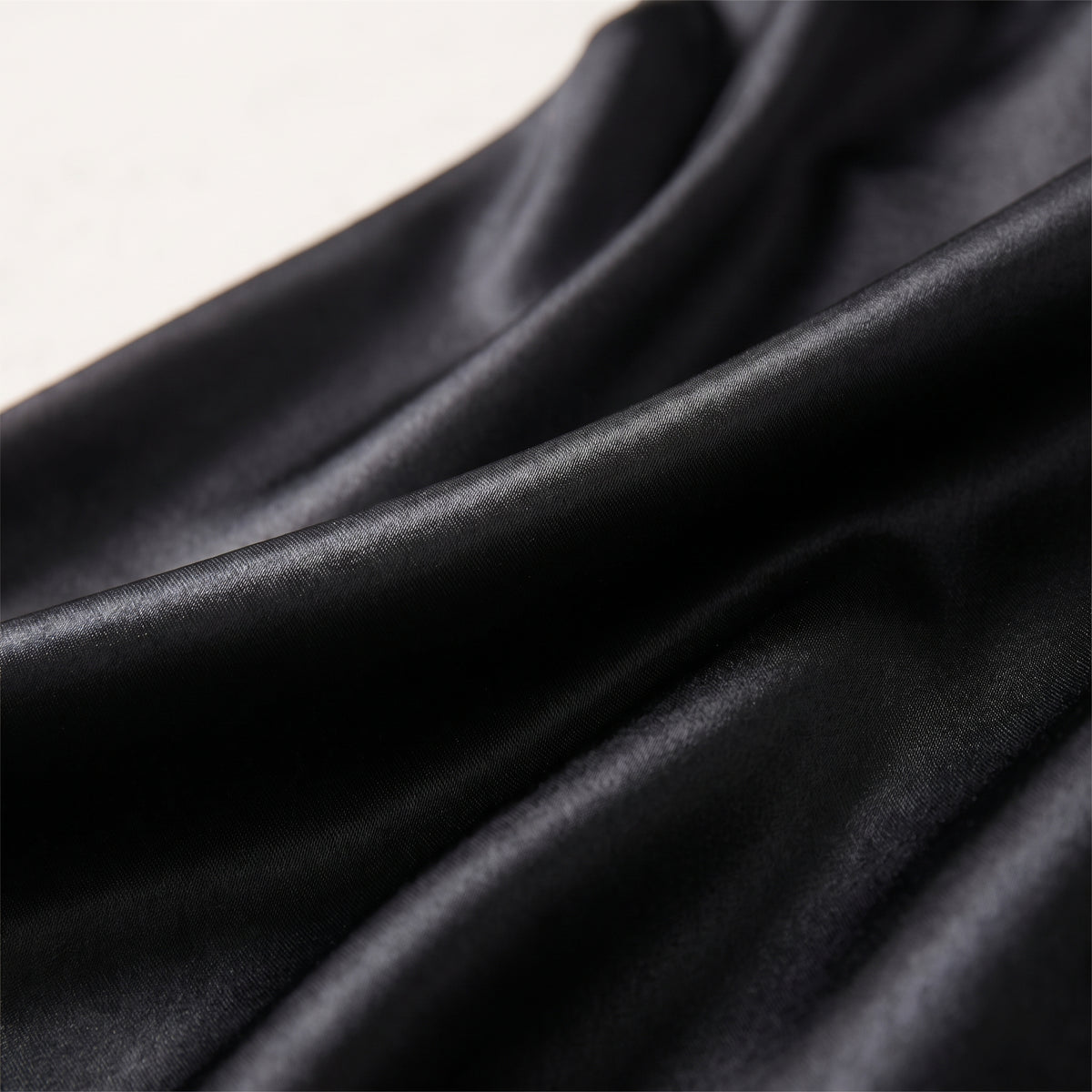 Détail du satin noir fluide et chatoyant de la longue jupe