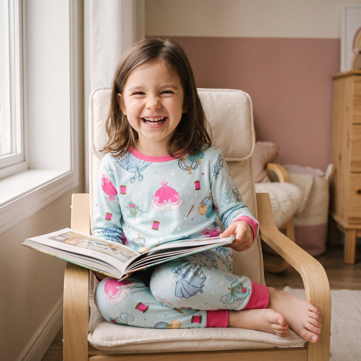 Petite fille lovée dans un fauteuil un matin de week-end, un livre ouvert sur les genoux
