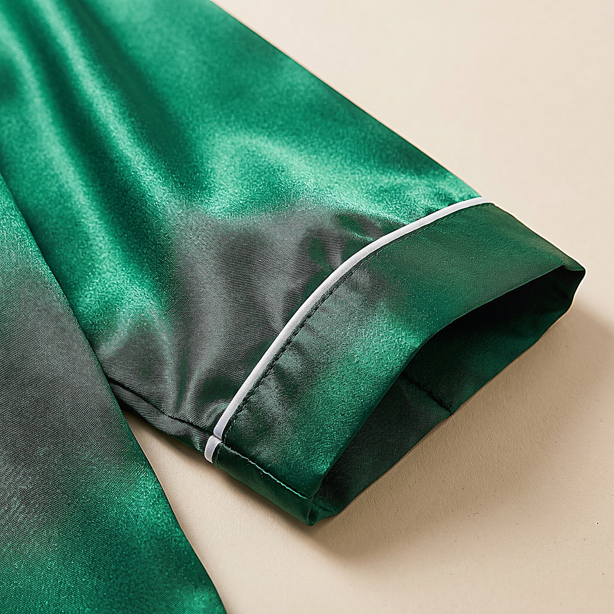 Détail du poignet à passepoil blanc et du satin vert émeraude lumineux