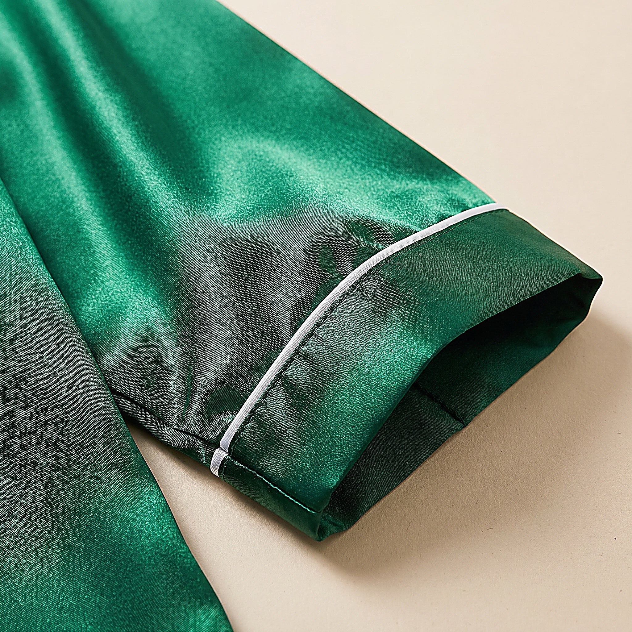 Détail du poignet à passepoil blanc et du satin vert émeraude lumineux Image