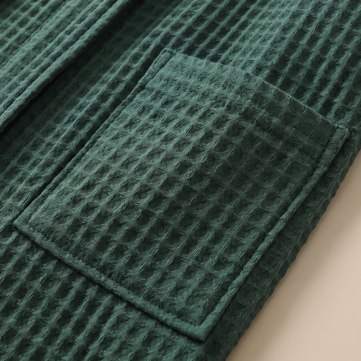 Détail d'une poche plaquée et de la maille nid d'abeille du peignoir vert sapin