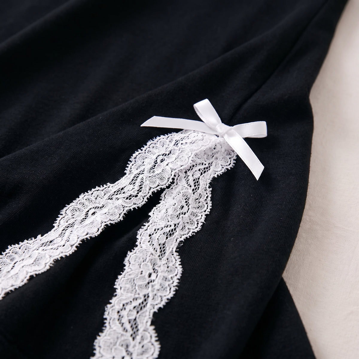 Détail de la fente latérale bordée de dentelle blanche et du noeud