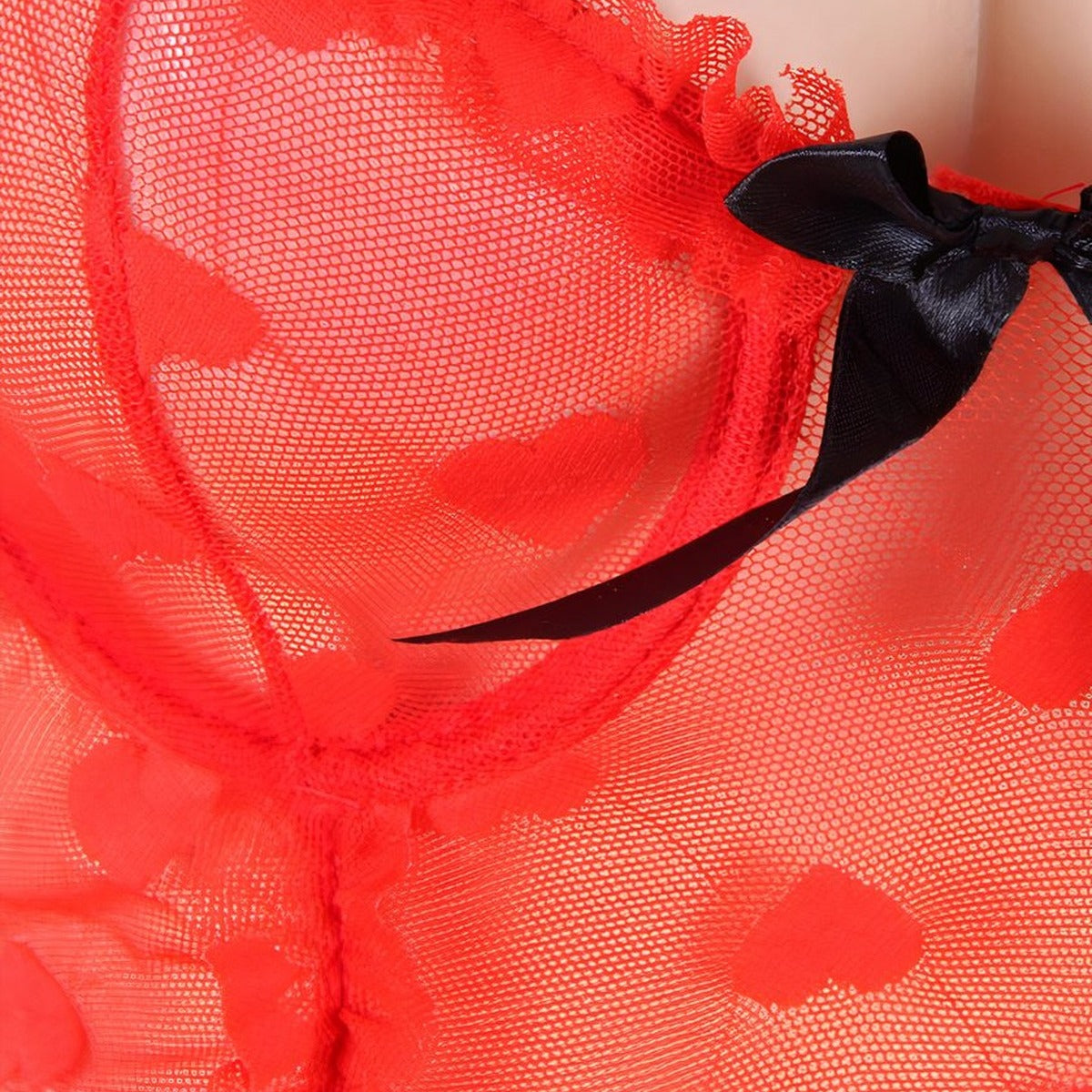 Macro detail du tissu en tulle rouge a coeurs, noeud en satin noir