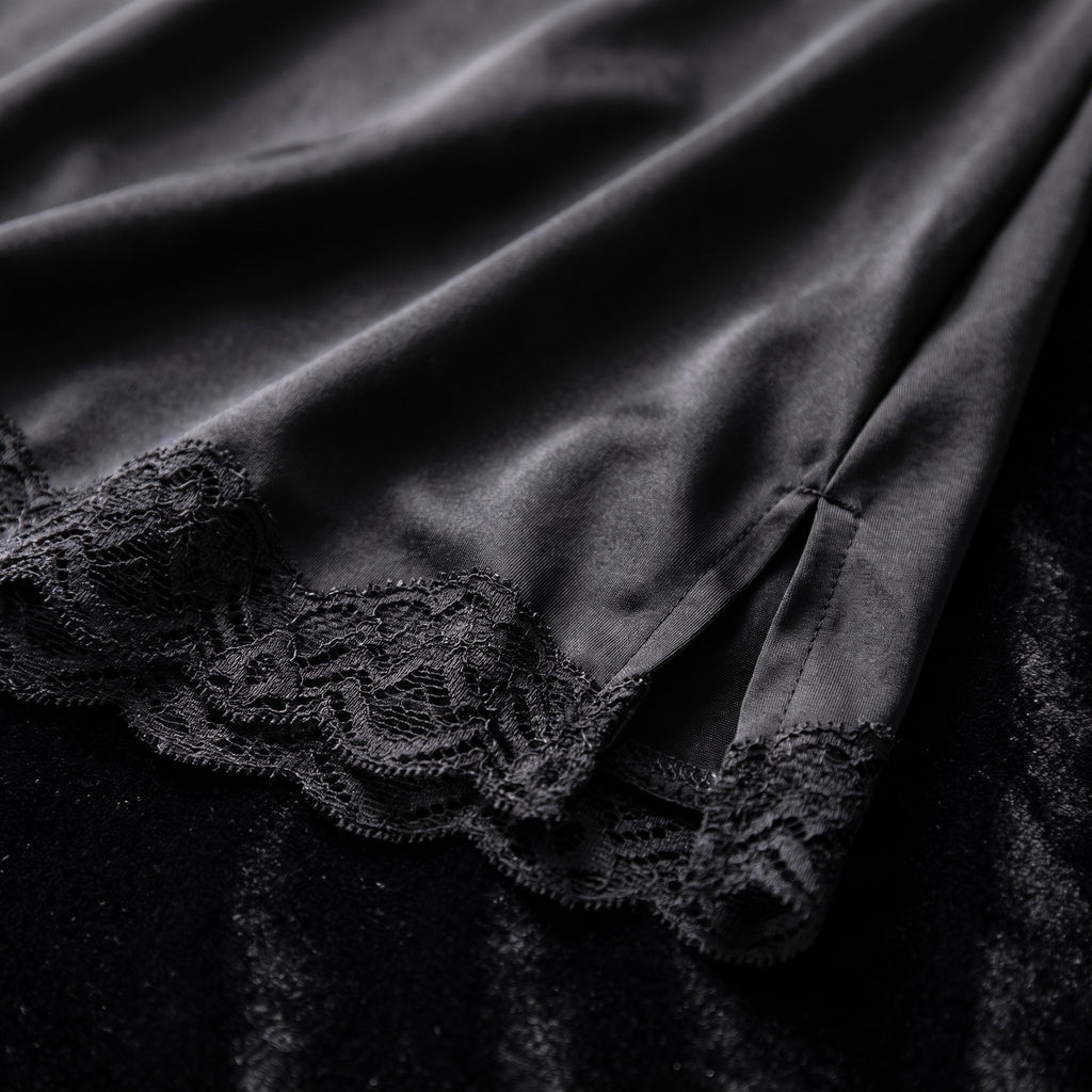 Détail de l'ourlet en satin noir bordé de dentelle festonnée et de la fente
