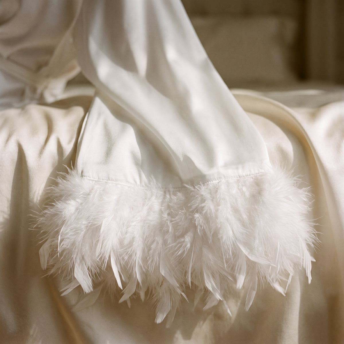 Manche de satin blanc posée sur un lit, la bande de plumes du poignet dépliée en gros plan