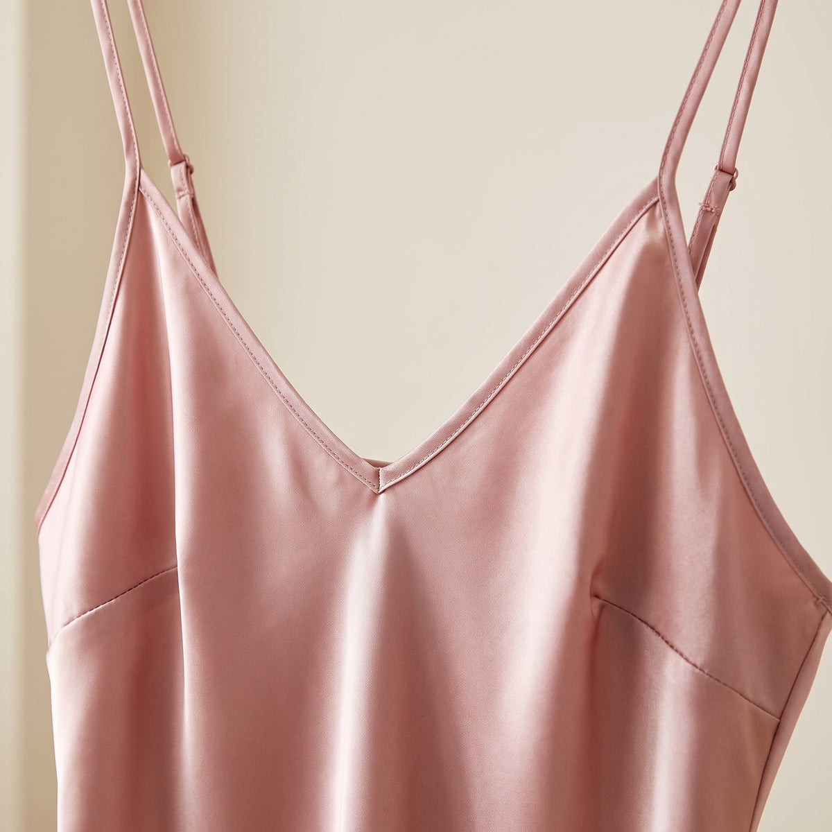 Détail du décolleté en V et des bretelles réglables de la nuisette satin rose