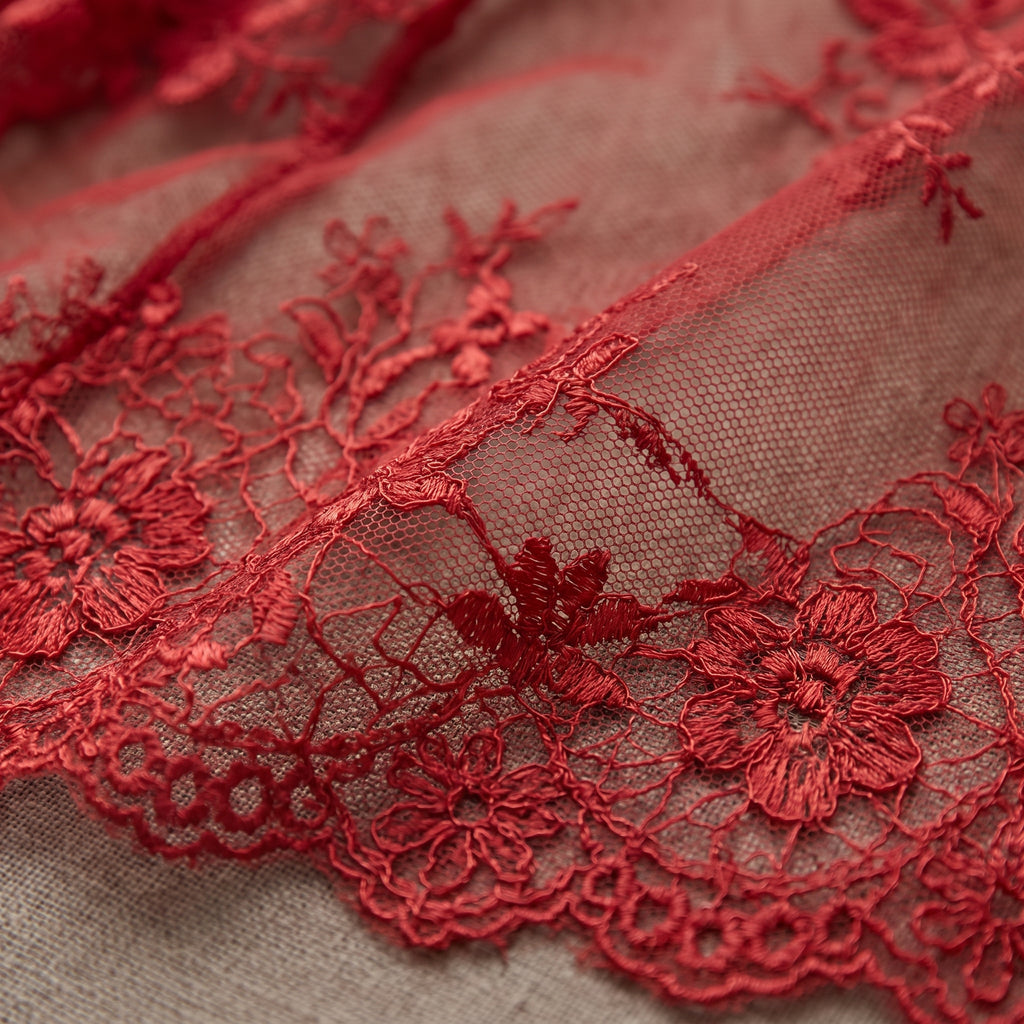 Détail de la dentelle rouge brodée transparente de la jupe