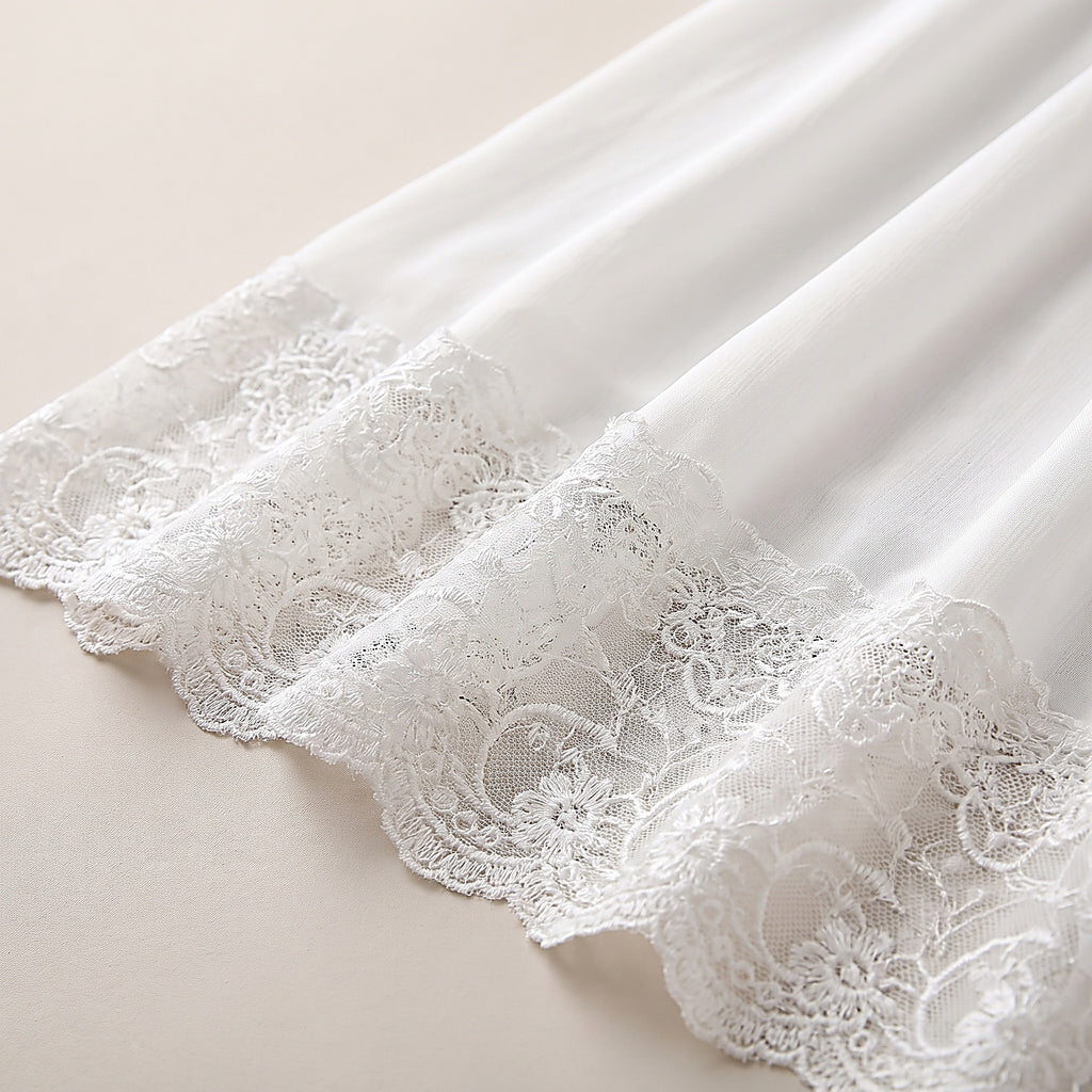Détail de l'ourlet en dentelle festonnée et du voile de mousseline blanc