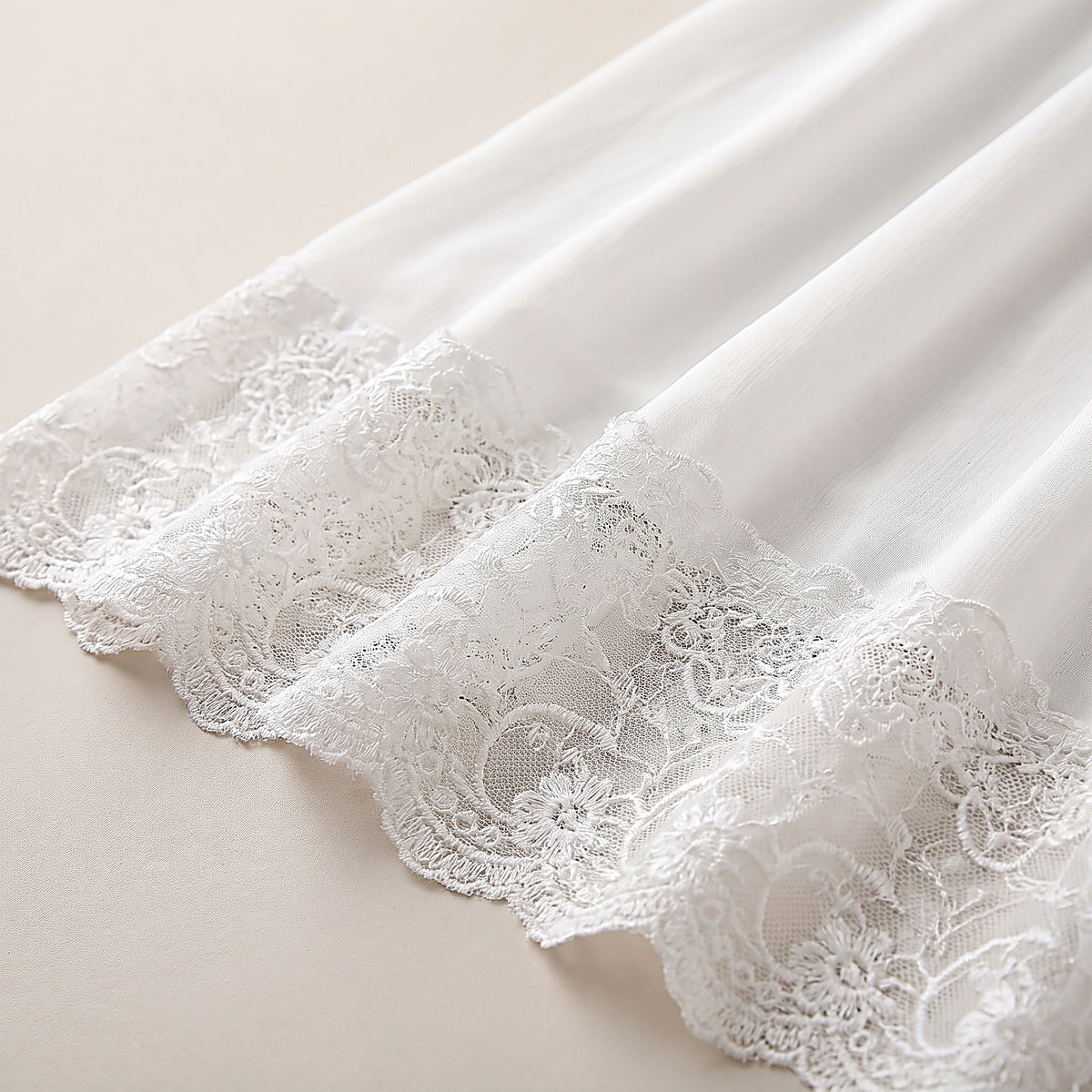Détail de l'ourlet en dentelle festonnée et du voile de mousseline blanc