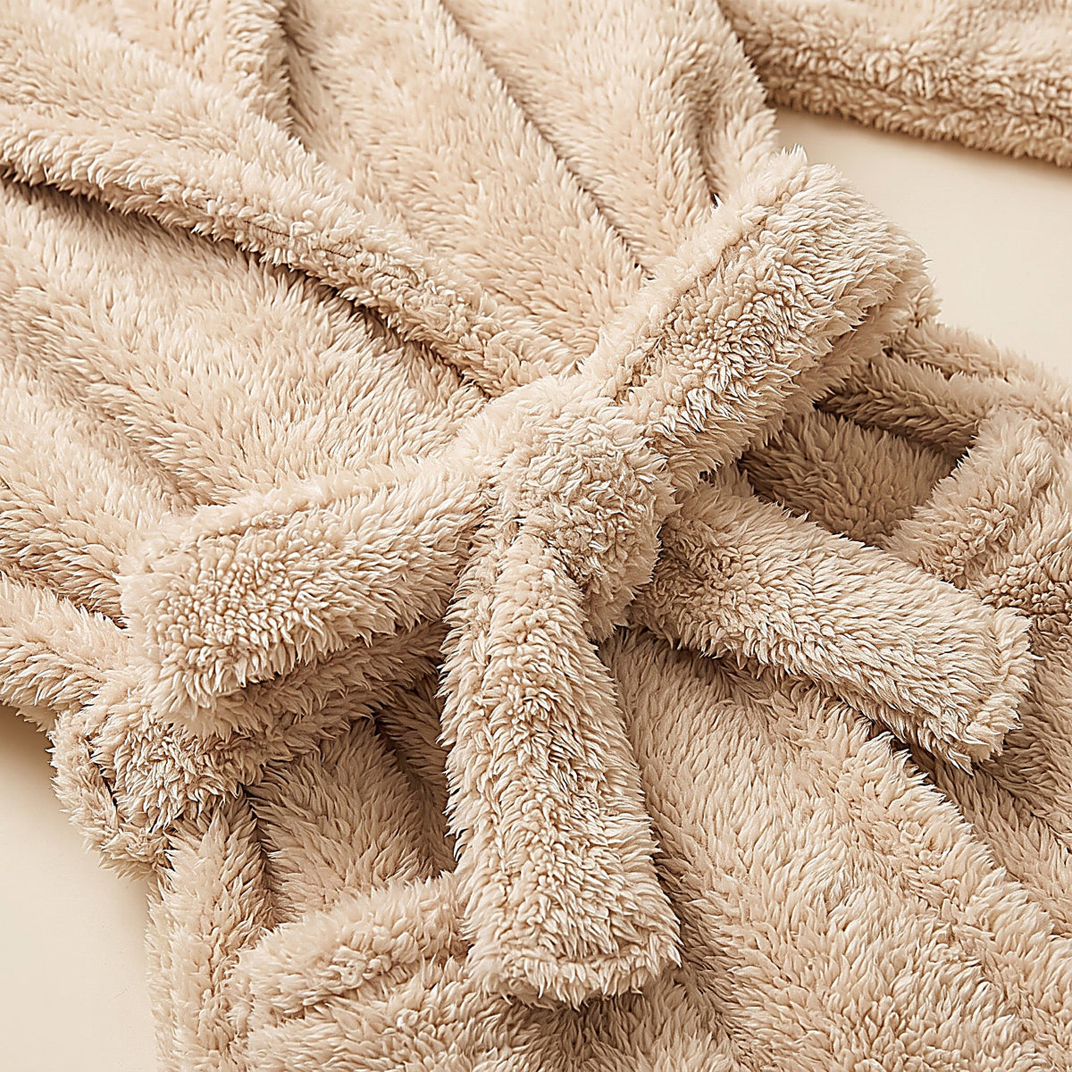 Détail de la fausse fourrure beige moelleuse à poil long et de la ceinture du peignoir