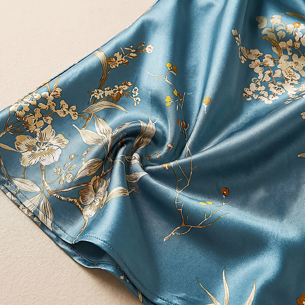 Détail du satin bleu pétrole et de l'imprimé floral doré