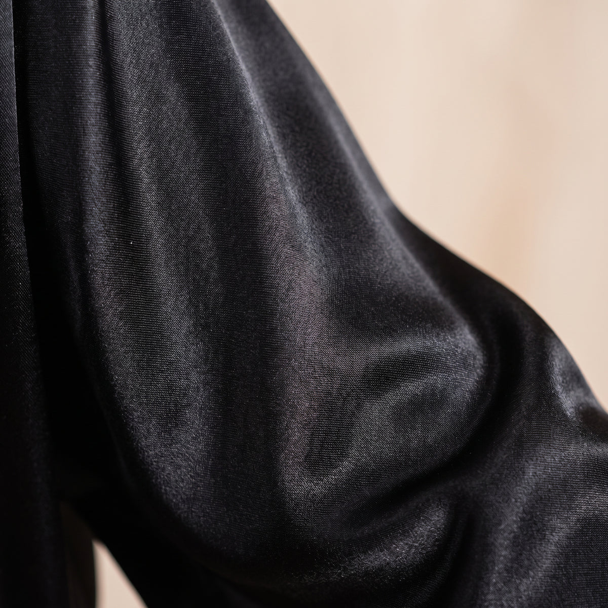 Détail du satin noir chatoyant de la manche du peignoir