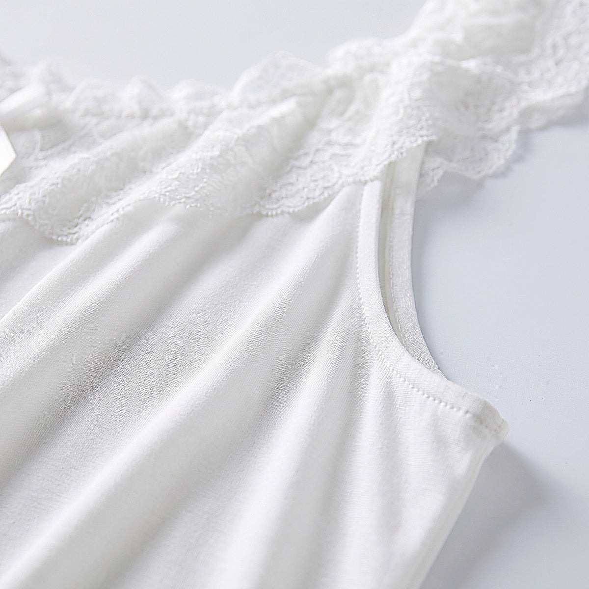 Détail de la matière modale blanche douce et de l'emmanchure en dentelle