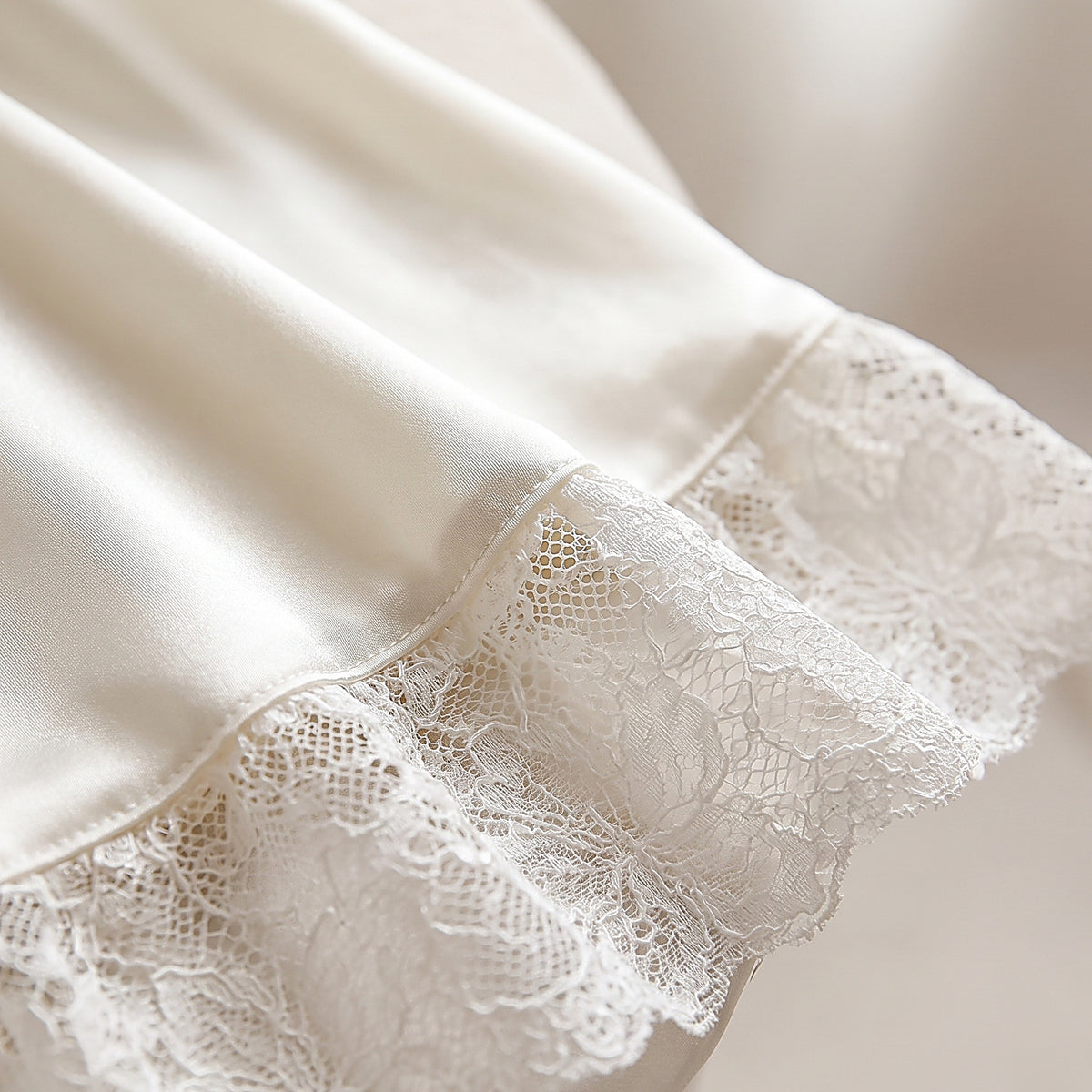 Détail de l'ourlet en dentelle et du satin ivoire lustré