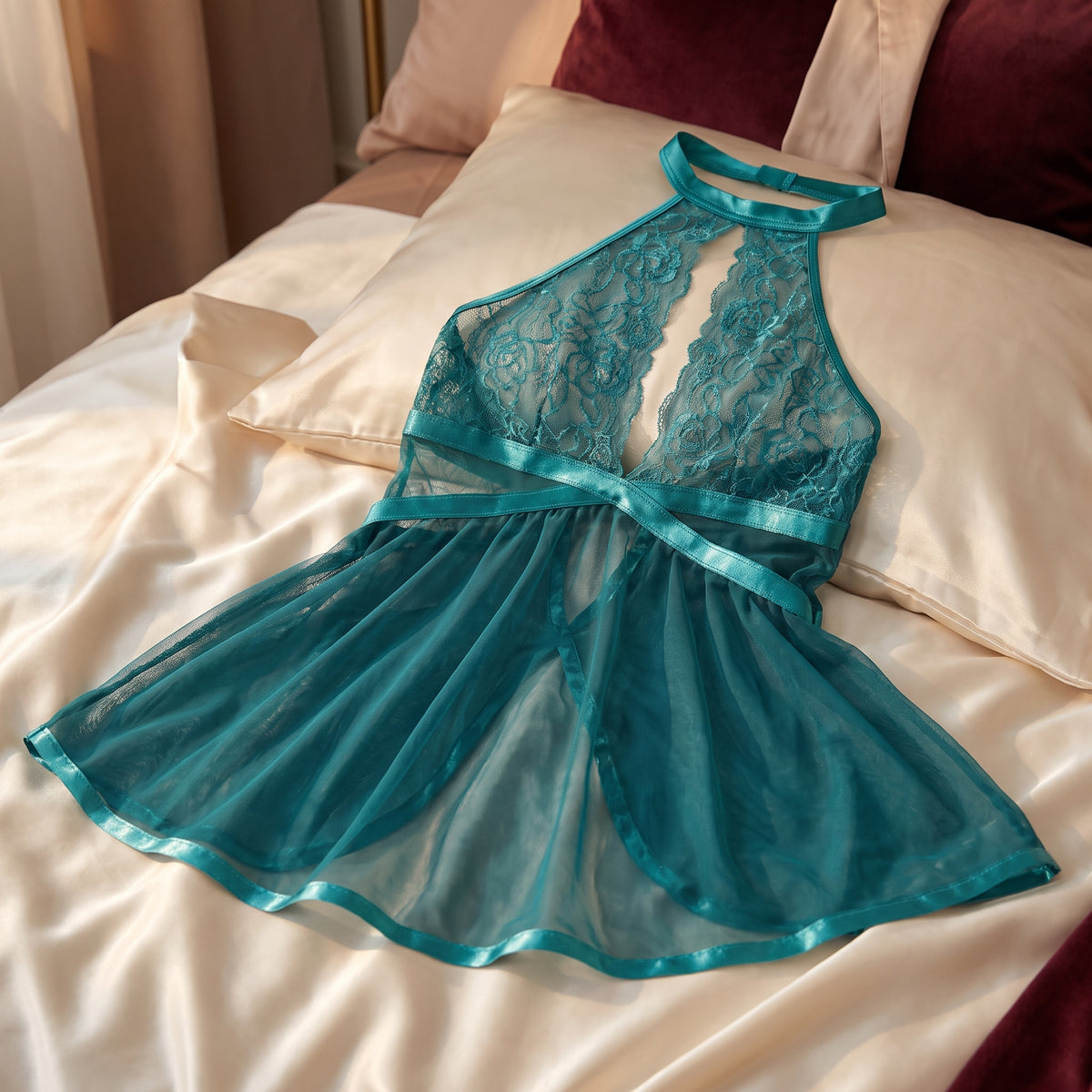 Nuisette bleu canard étalée sur un lit, taille croisée de satin et ourlet satiné