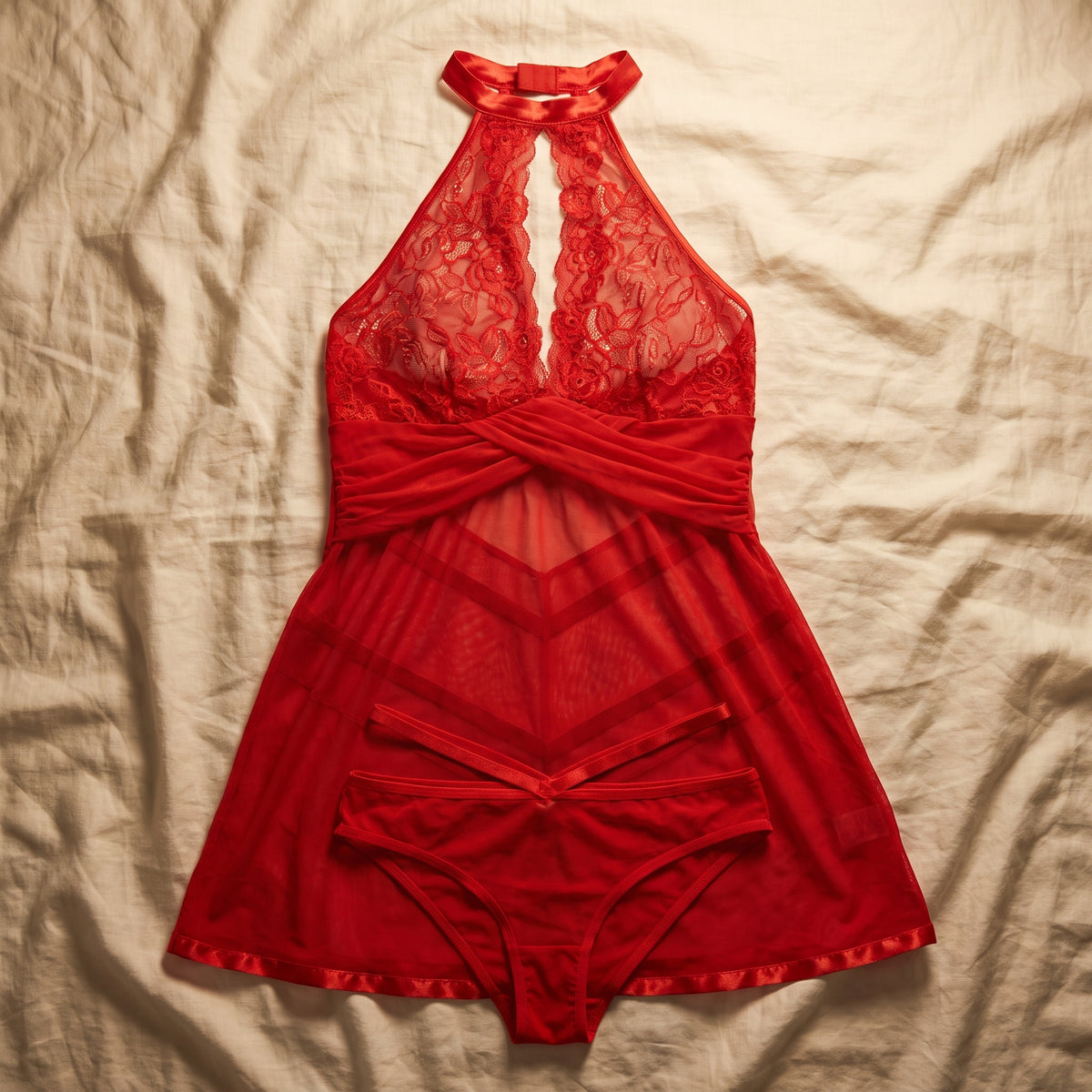 Nuisette rouge et sa culotte assortie posées à plat sur un drap crème