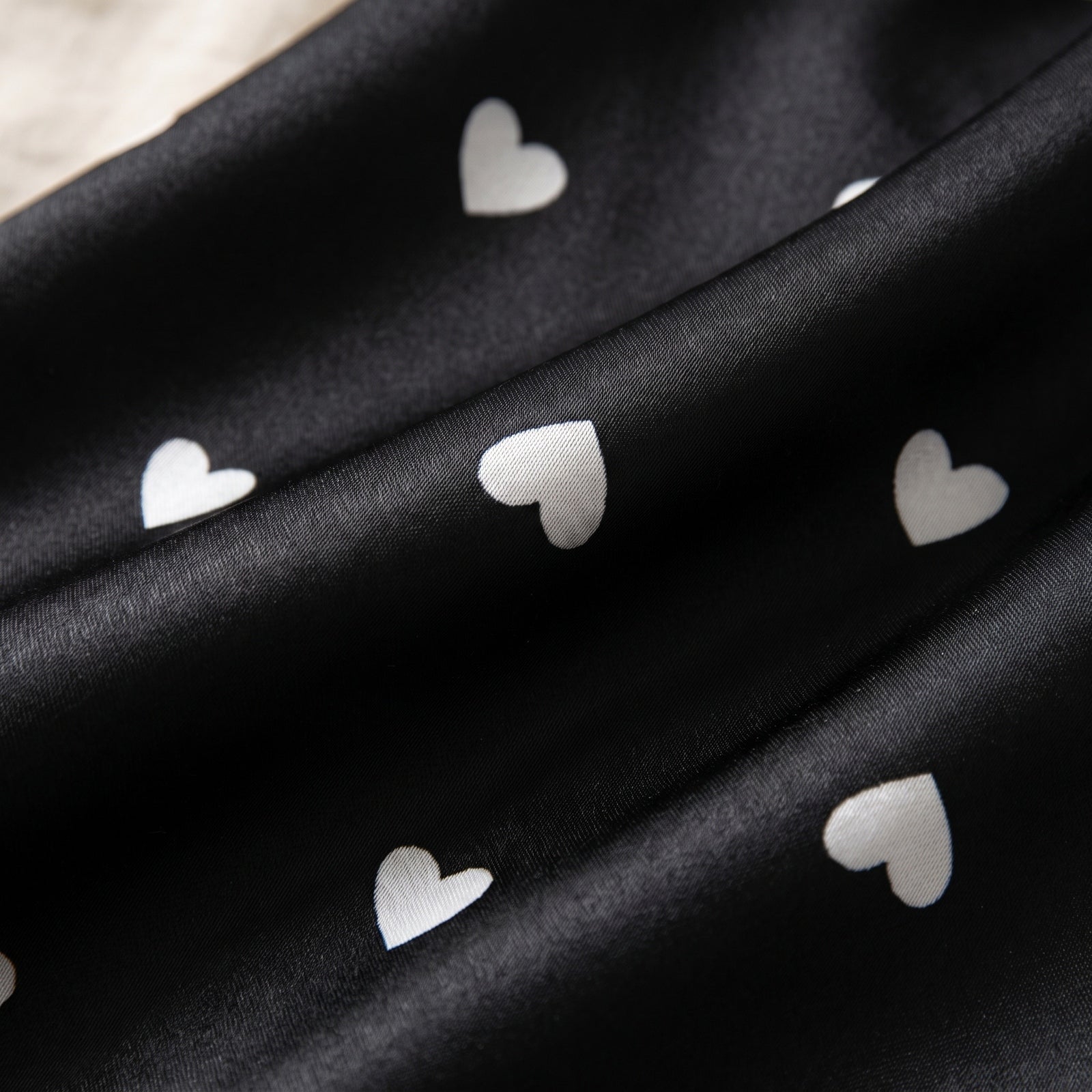 Les petits cœurs blancs semés sur le satin noir Image