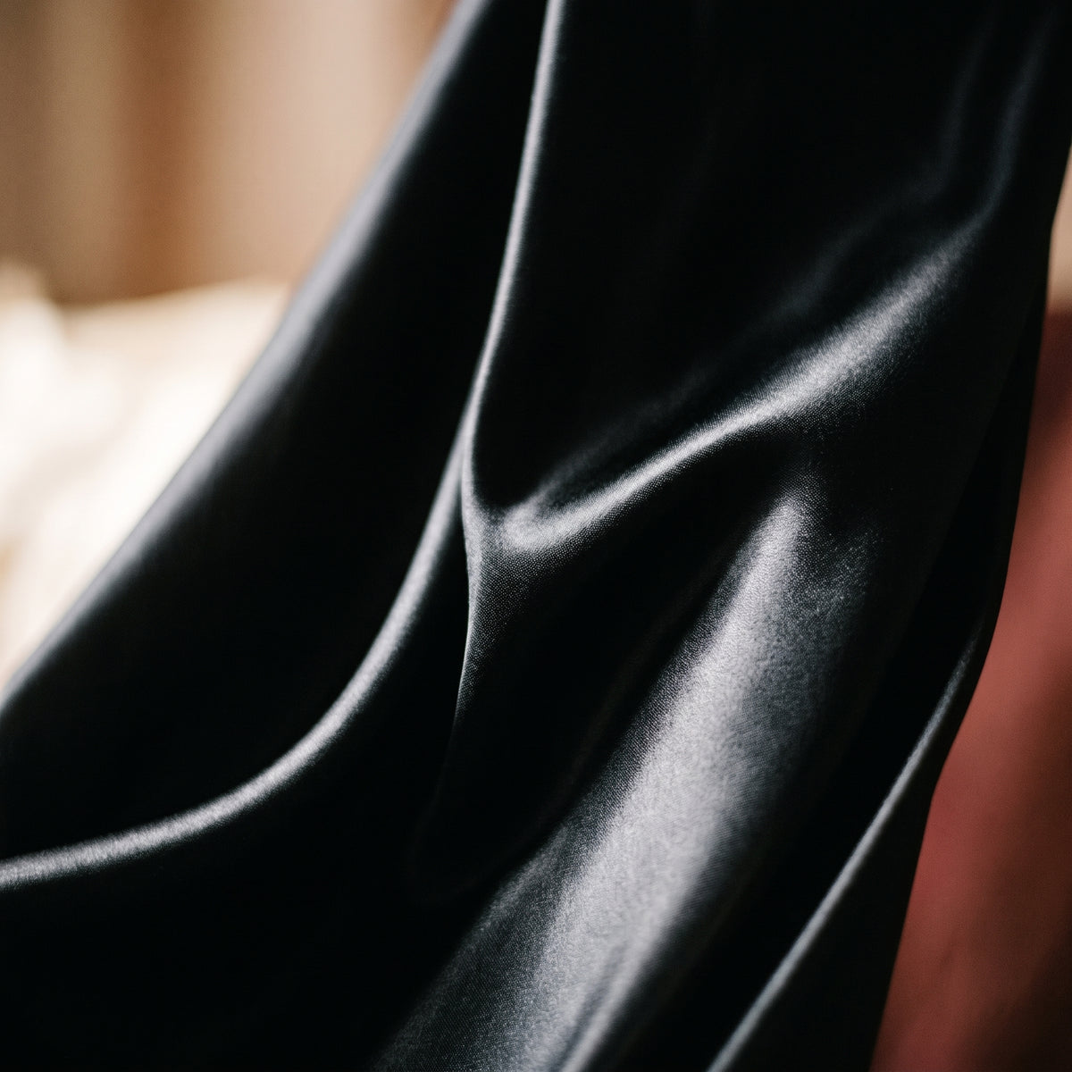 Le satin noir profond et fluide de la nuisette, plis et reflets de lumière