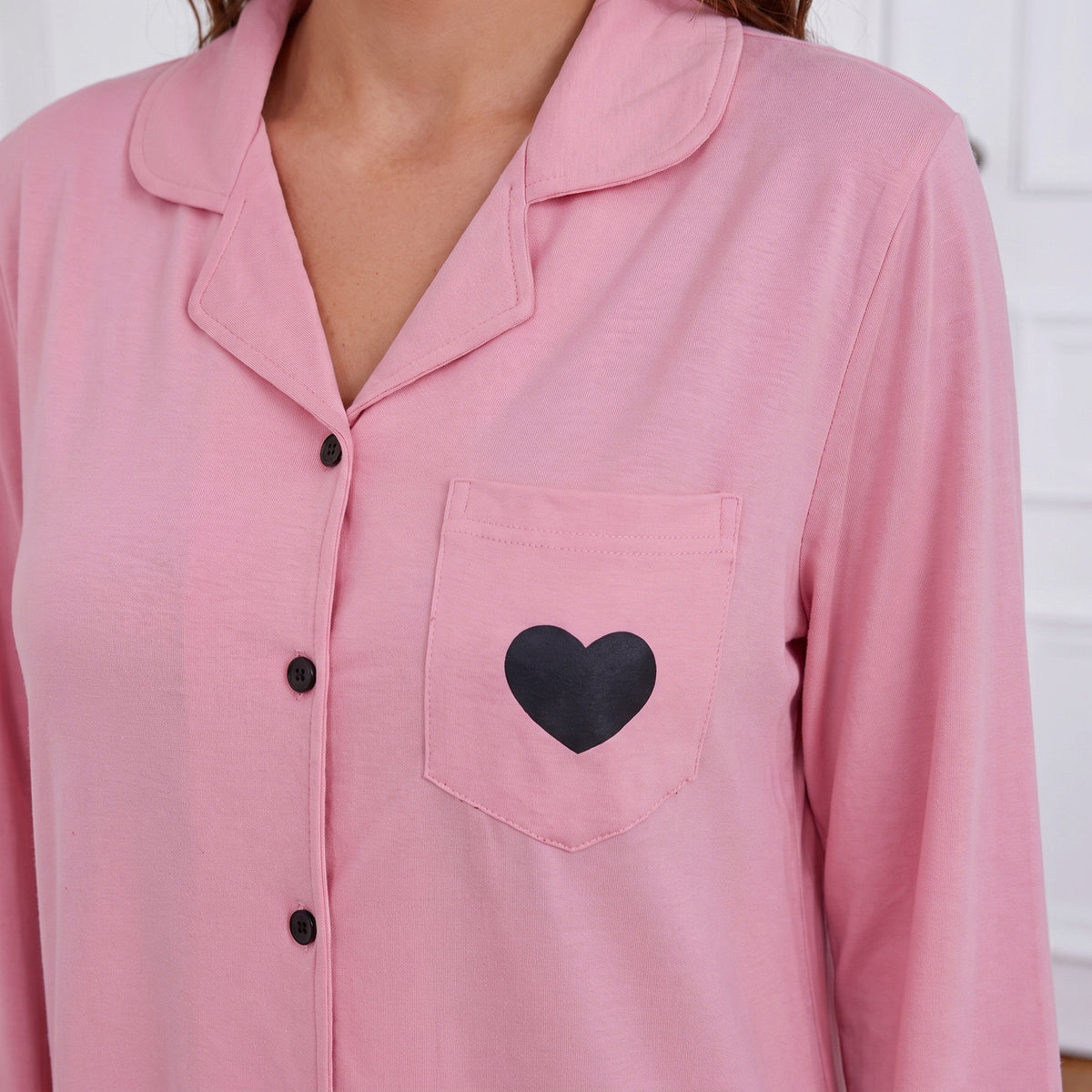 Col à revers et cœur noir sur la poche de la chemise de nuit rose