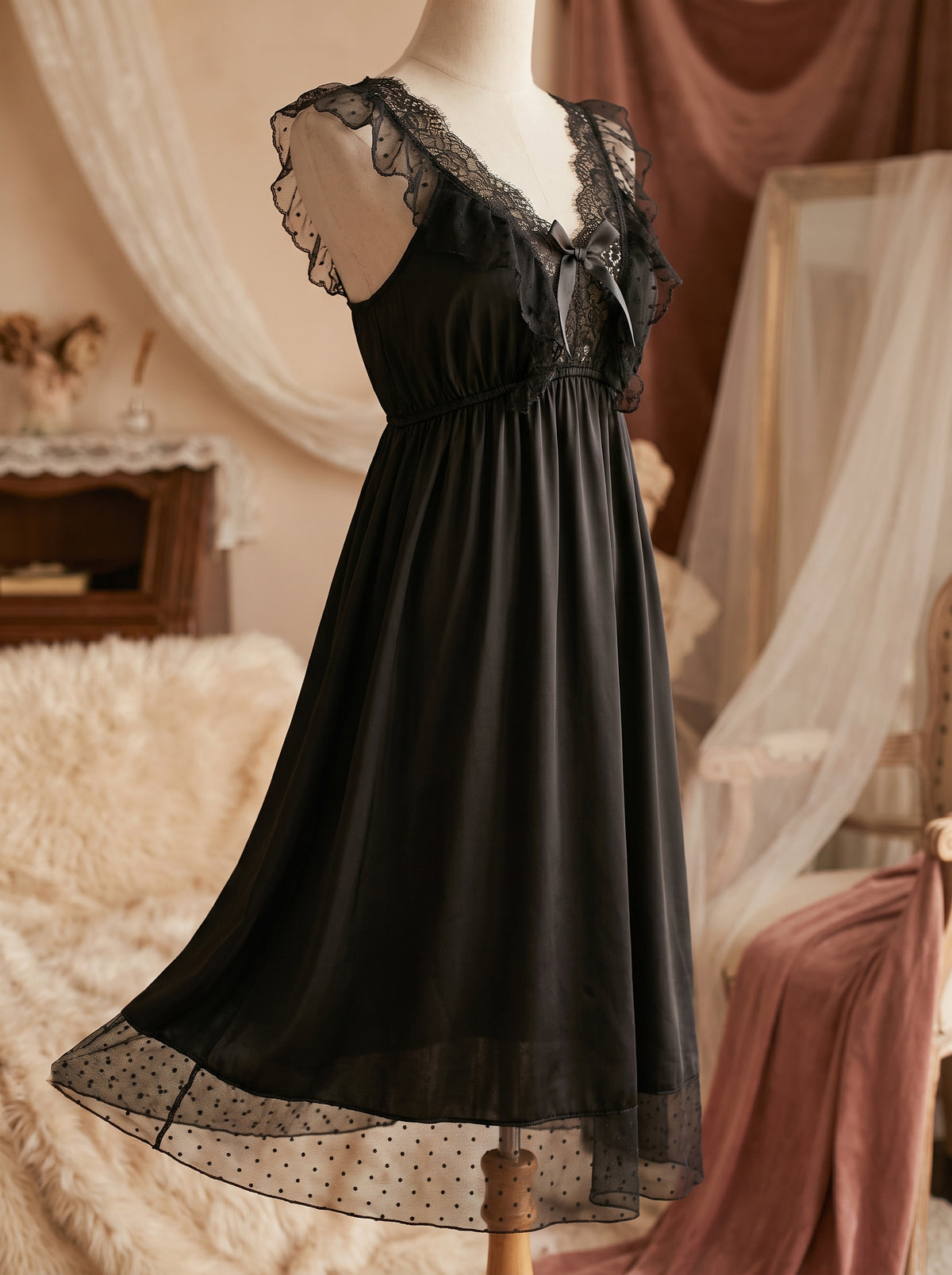 Chemise de nuit noire en satin et dentelle portée sur mannequin, coupe empire et ourlet en tulle à pois