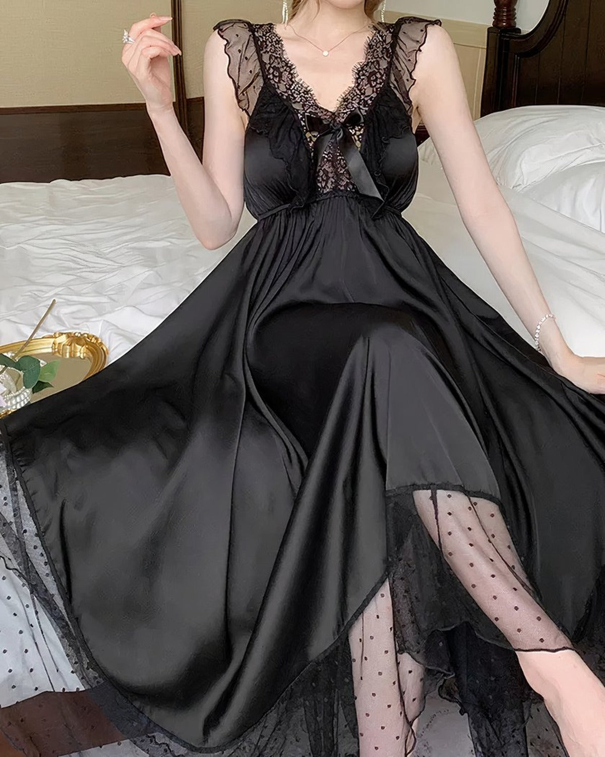 Détail de la chemise de nuit noire en satin, dentelle du décolleté et noeud satiné