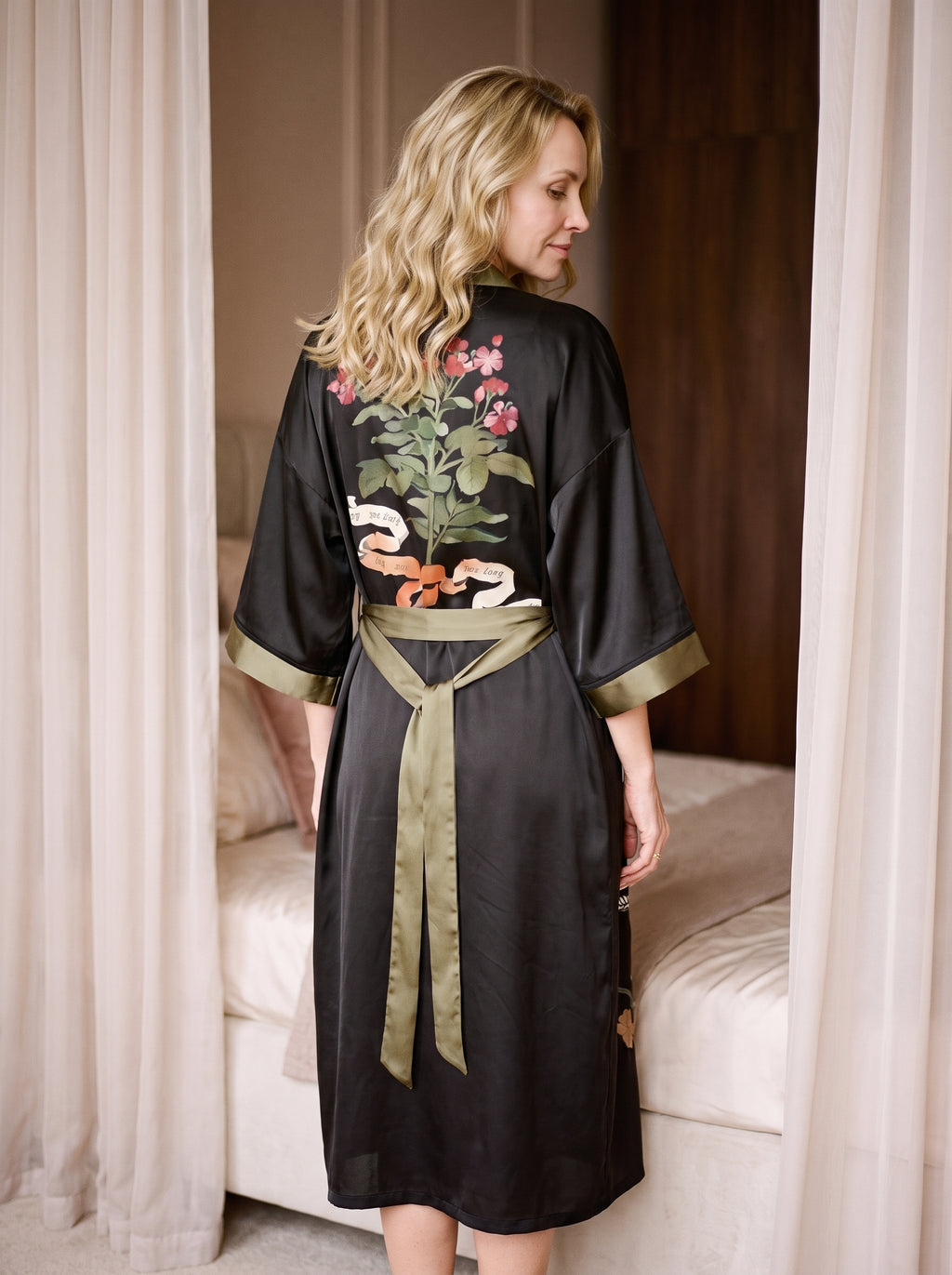 Peignoir kimono noir porté de dos, grand bouquet fleuri entre les épaules et ceinture vert kaki nouée dans le dos