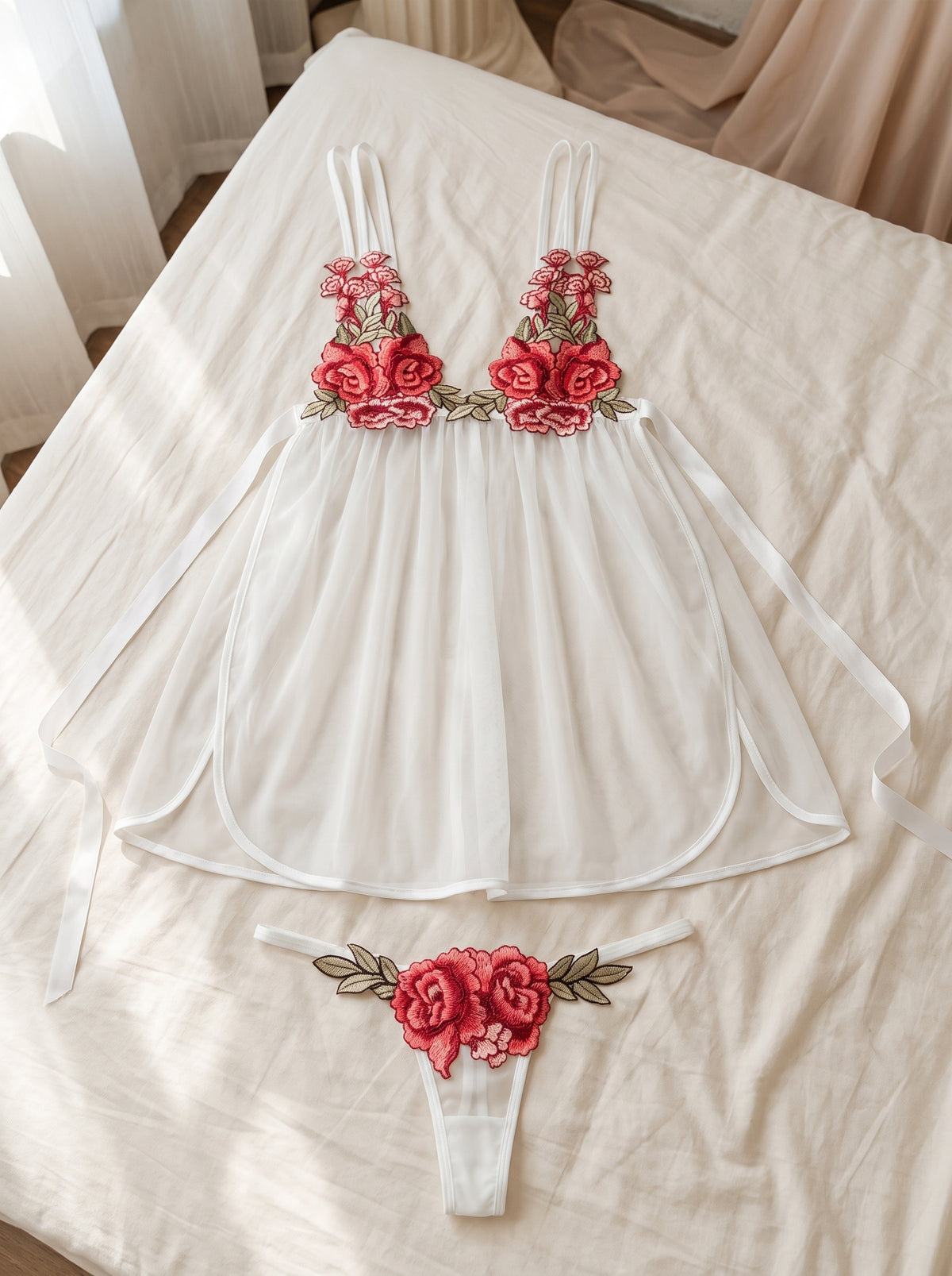 Les deux pièces posées à plat sur un drap crème, la nuisette déployée et son bas assorti à la même applique de roses brodées